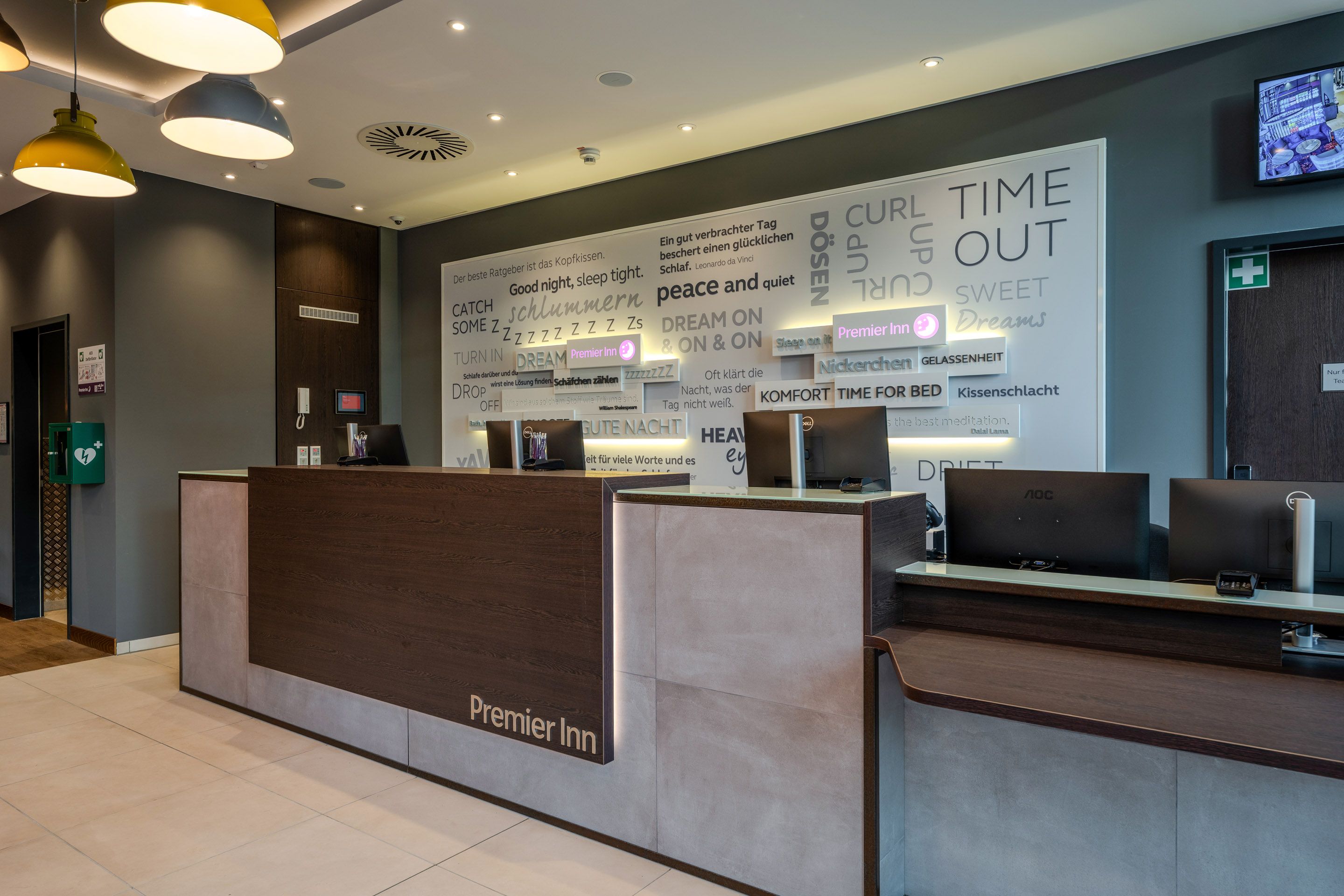 Rezeption eines Premier Inn Hotels mit moderner Einrichtung und Wandzitaten.