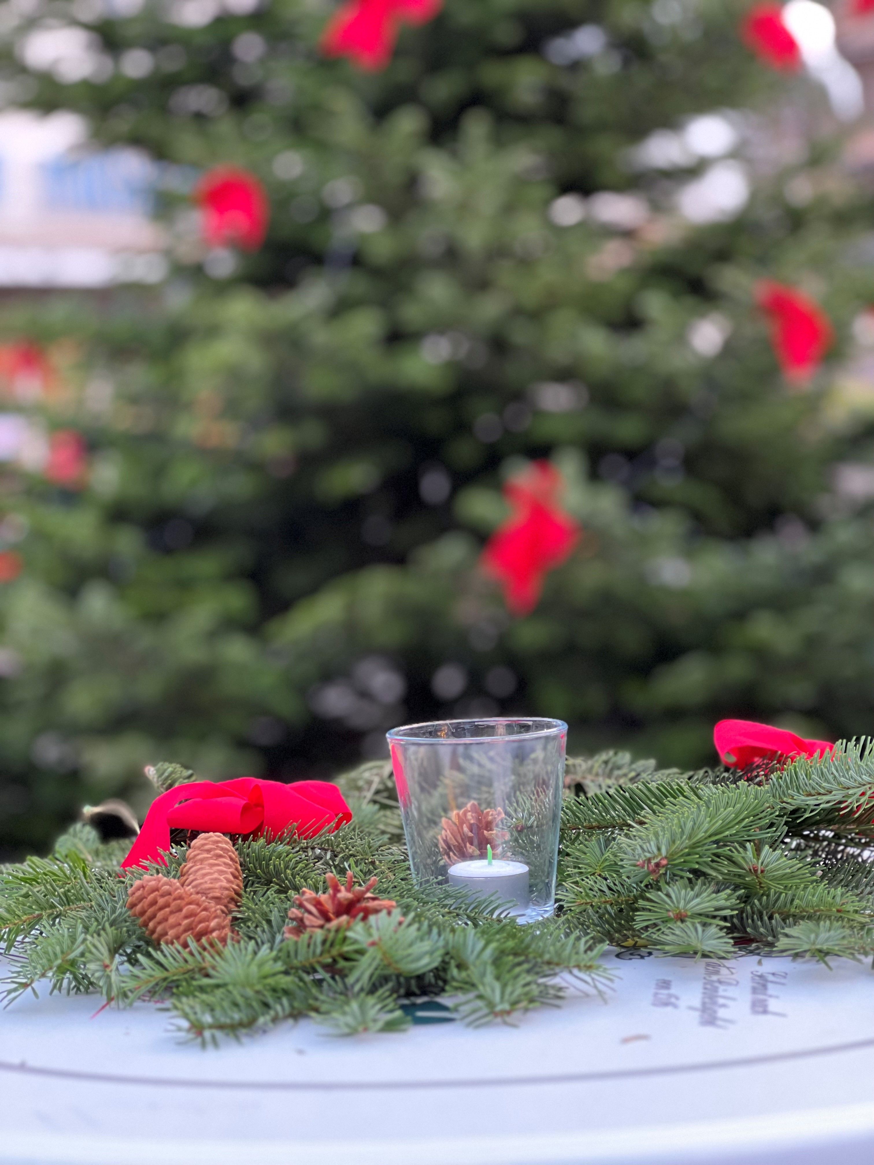 Adventskranz mit roten Schleifen und Tannenzapfen auf einem Tisch auf dem Herdecker Weihnachtszauber.