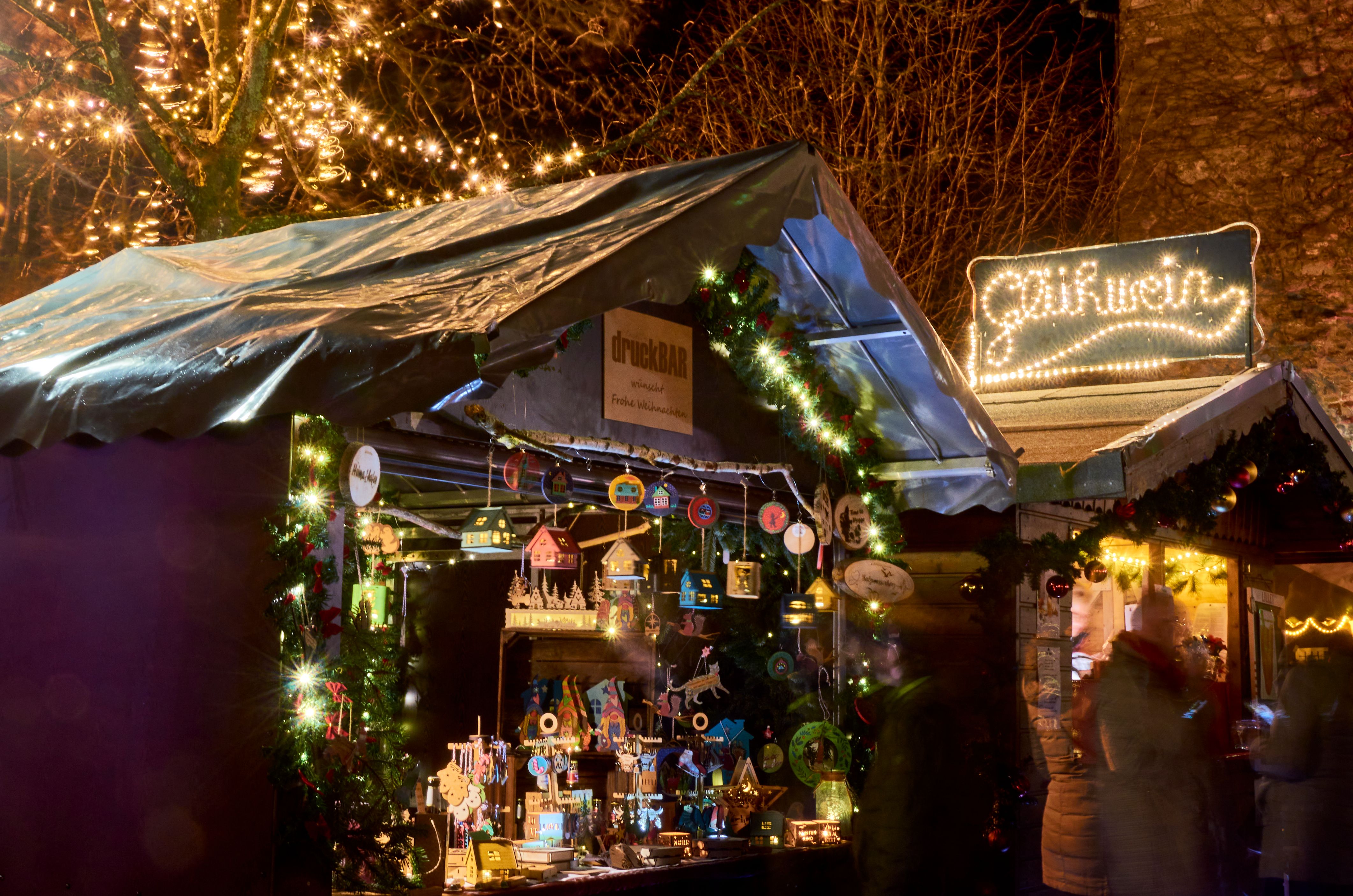 Ein festlich beleuchteter Stand auf dem Weihnachtsmarkt in Kürten, geschmückt mit Lichtern und weihnachtlichen Dekorationen.