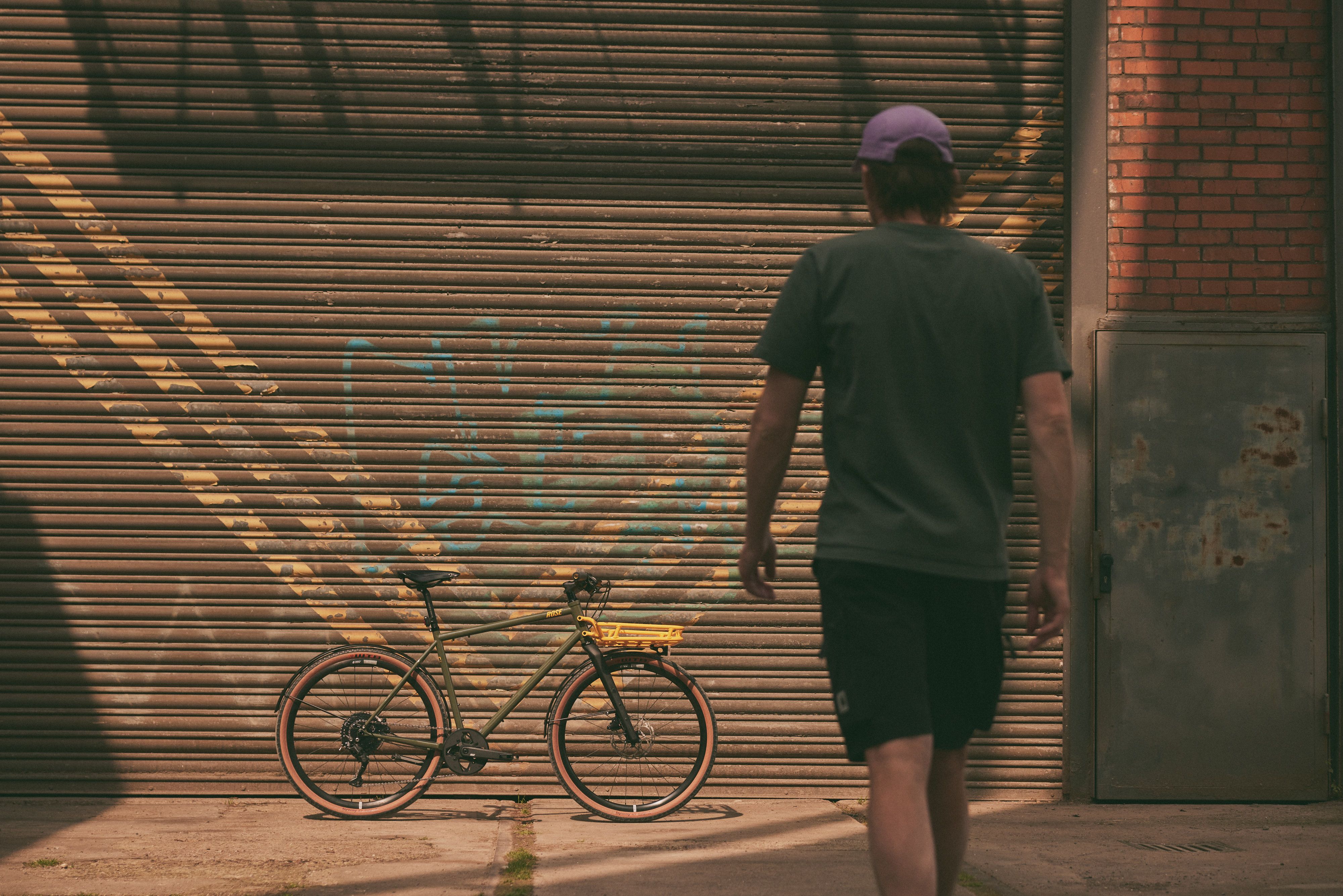 Gravelbike steht auf einem Industriegelände mit alten Rohren und Gebäuden im Hintergrund.