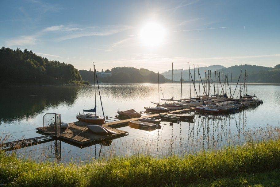 Boote am Hennesee bei Sonnenuntergang, umgeben von bewaldeten Hügeln.