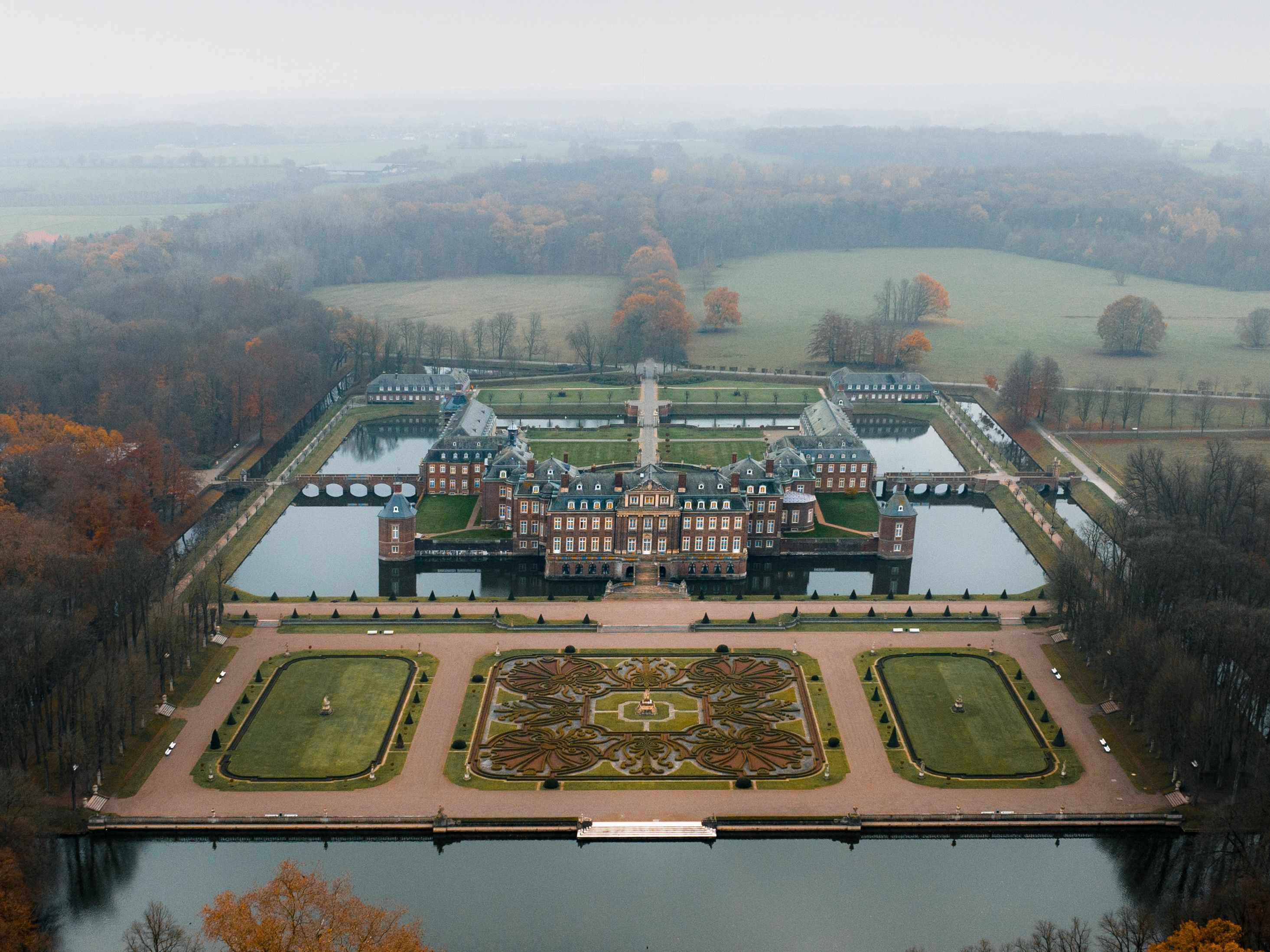Schloss und Park von oben bei leichtem Nebel im Herbst 