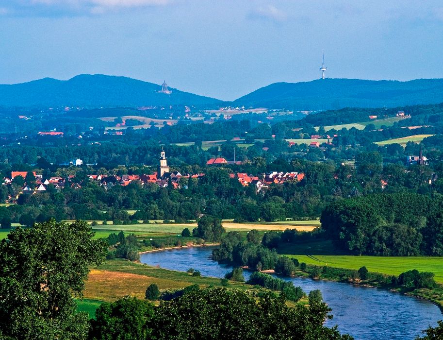Blick auf die Stadt Porta Westfalica. Landschaft mit Fluss, Stadt und Hügeln im Hintergrund.