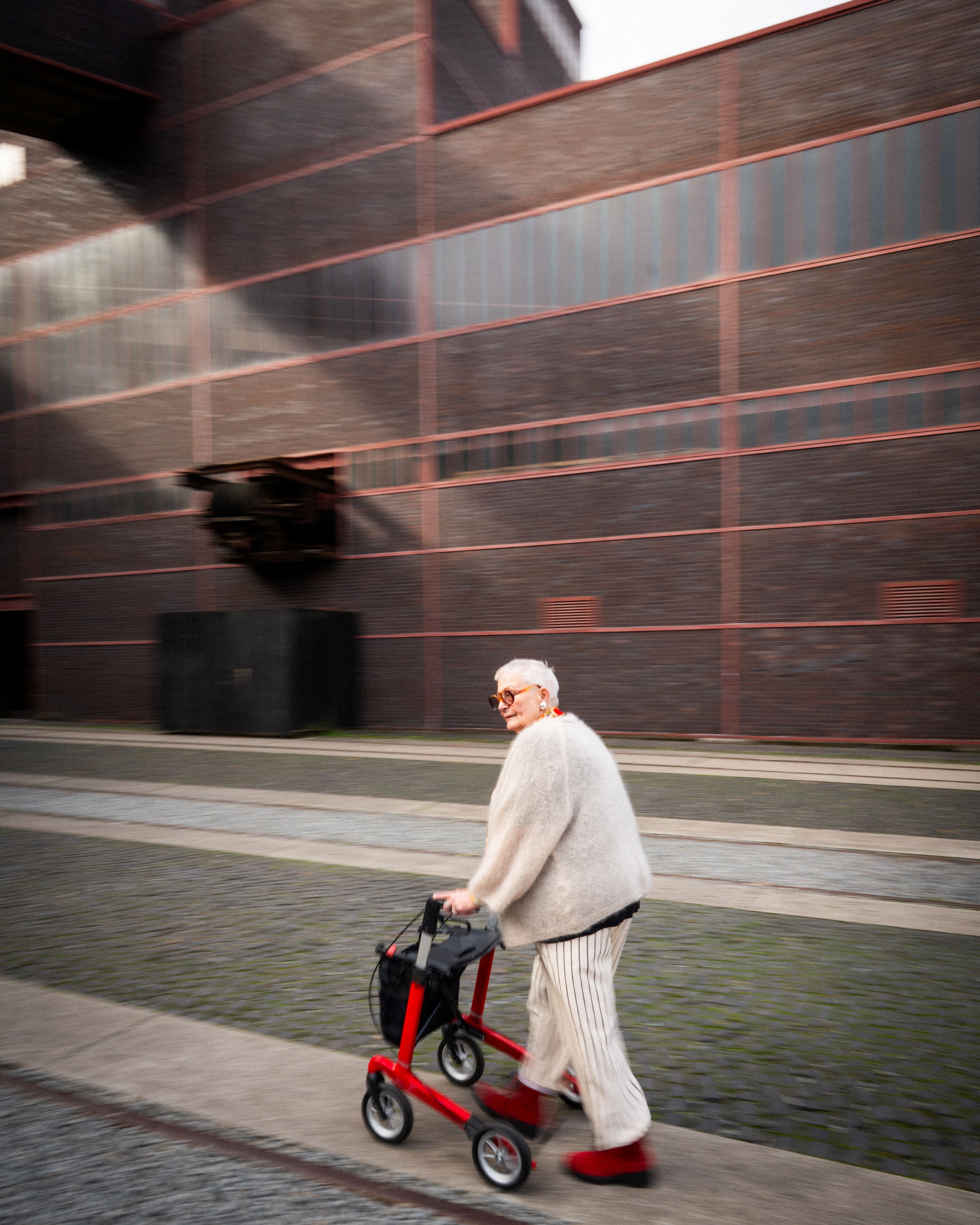 Eine ältere Dame ist mit ihrem Rollator auf dem Gelände des Welterbes Zollverein unterwegs