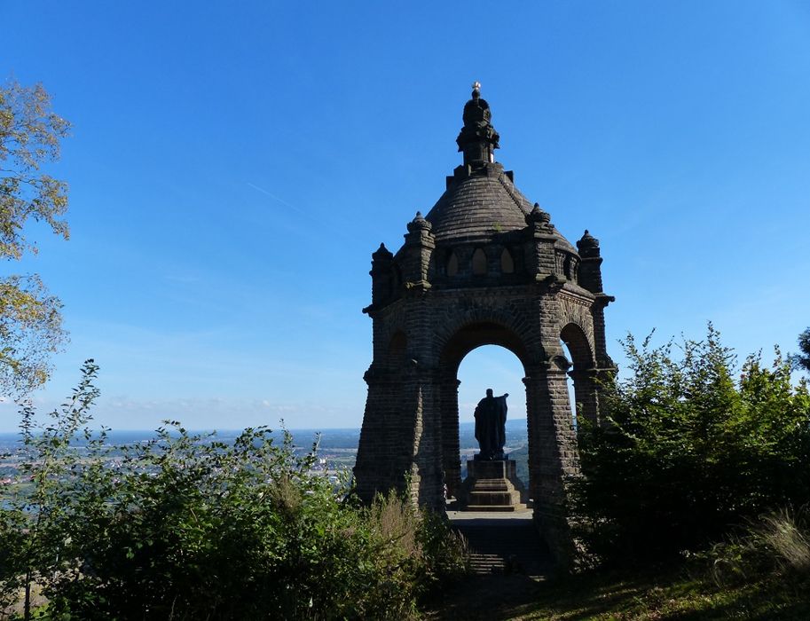 Das Kaiser-Wilhelm-Denkmal vor blauem Himmel, umgeben von Bäumen, mit weitem Blick über die Landschaft.