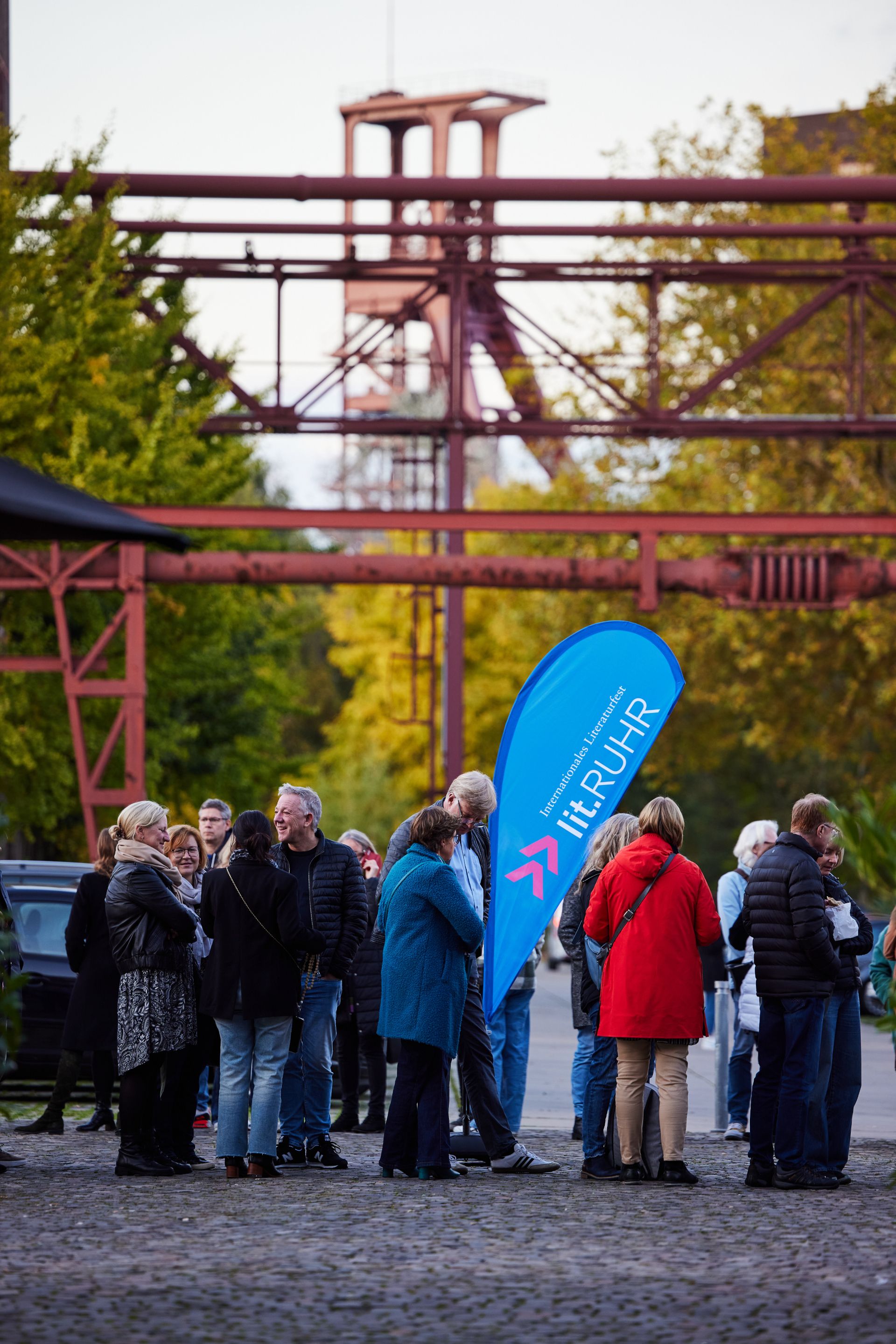 Literaturbegeisterte warten vor den historischen Industriegebäuden der Zeche Zollverein auf den Einlass zur lit.RUHR
