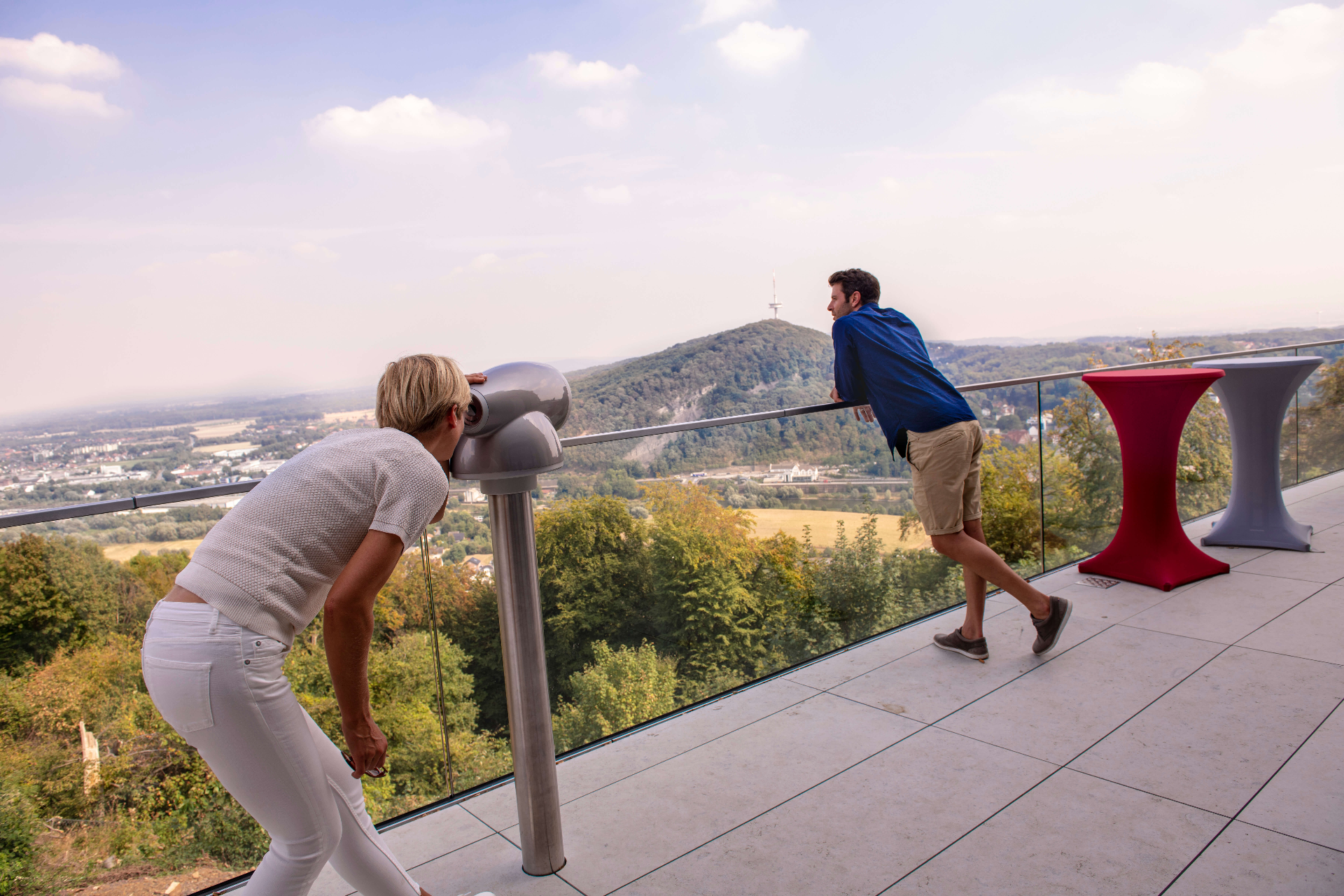 Ein Paar betrachtet vom Kaiser-Wilhelm Denkmal die umliegende Landschaft. Die Frau schaut dabei durch ein Fernrohr.