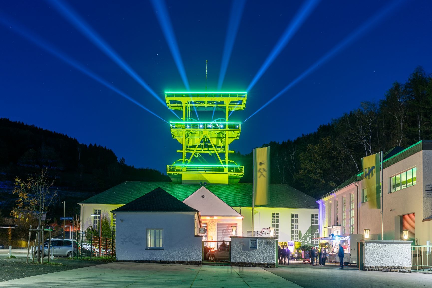 Ein beleuchteter Förderturm in Lennestadt strahlt nachts in grünem Licht. 
