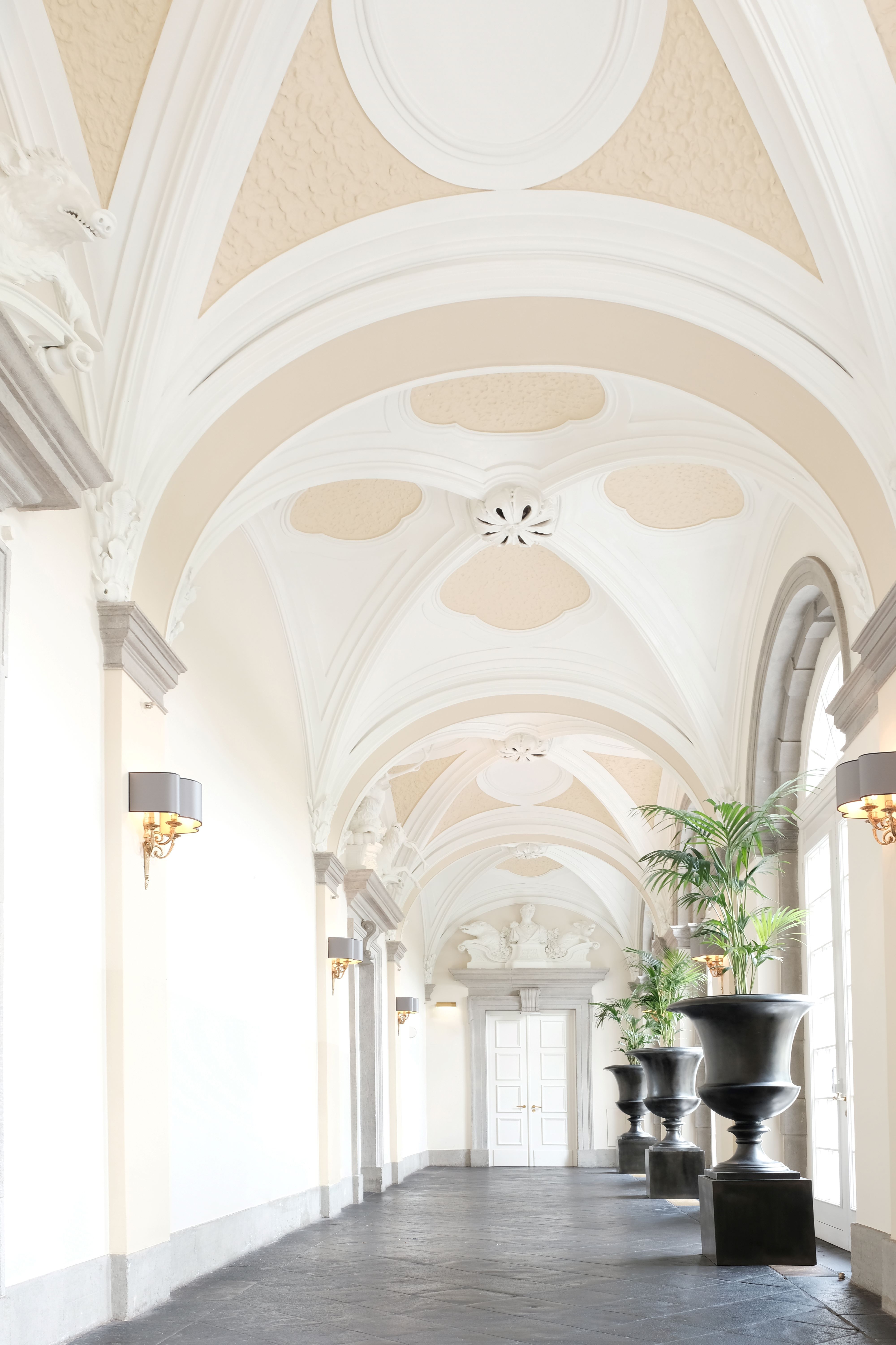 Schwarze Vasen säumen den in weiß und grau gehaltenen Arkadengang im Schloss