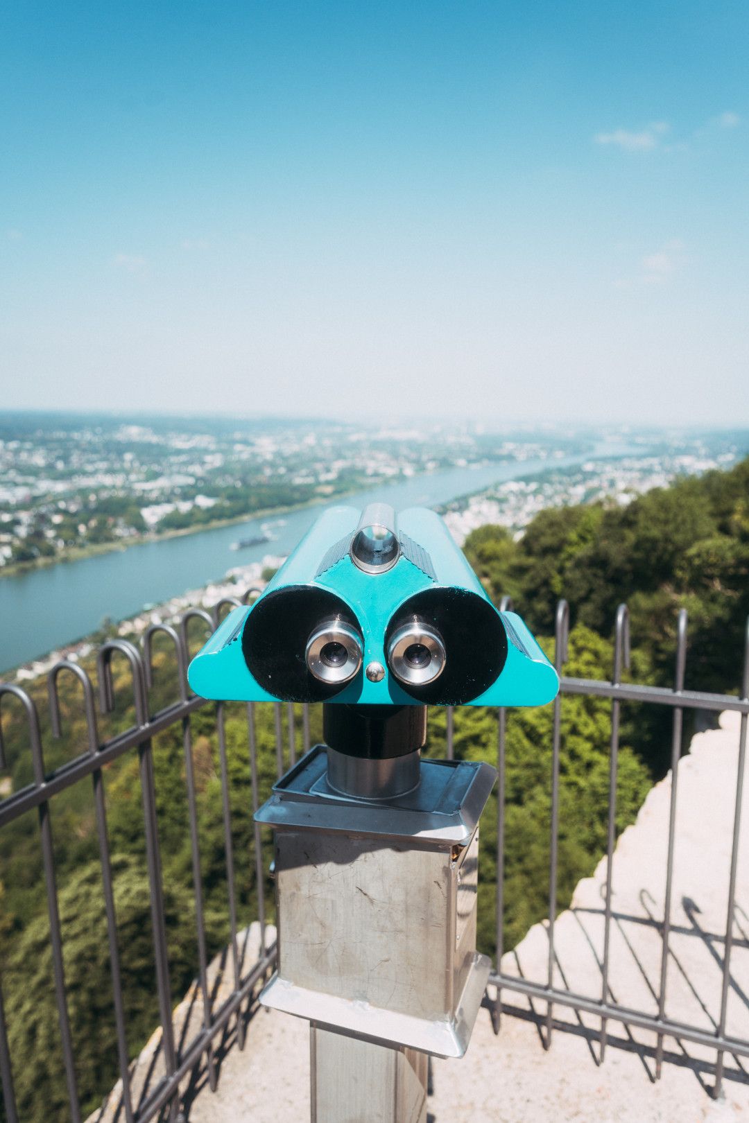 Ein Fernglas auf einem Aussichtspunkt mit Blick auf den Rhein und die umliegende Landschaft.