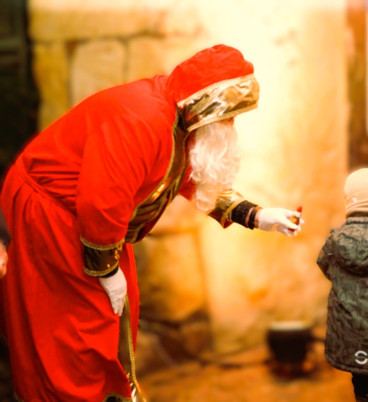 Nikolaus in rotem Gewand überreicht einem Kind ein Geschenk auf dem Tecklenburger Nikolausmarkt.