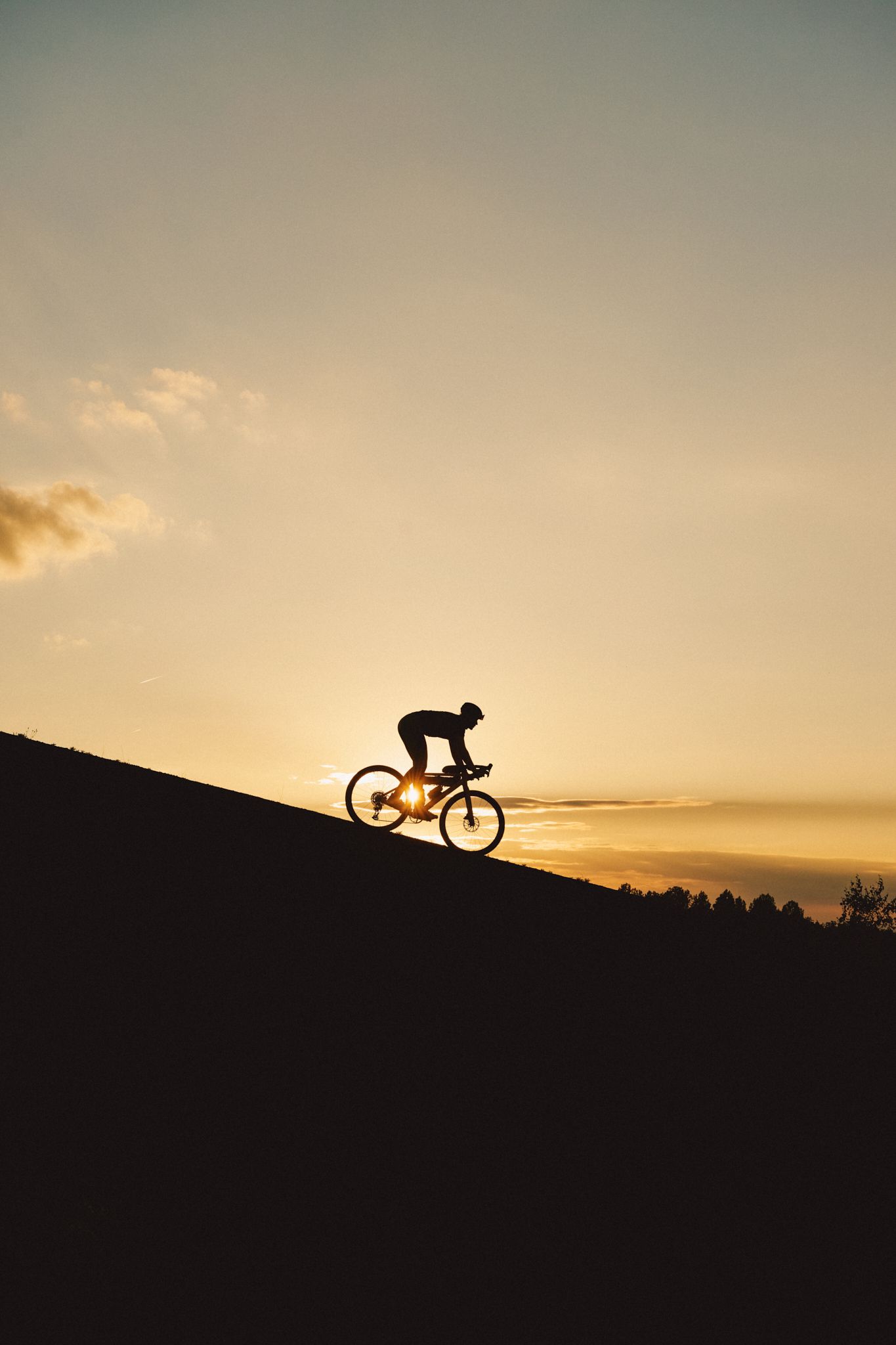 Person fährt bergab mit Gravelbike im Sonnenuntergang