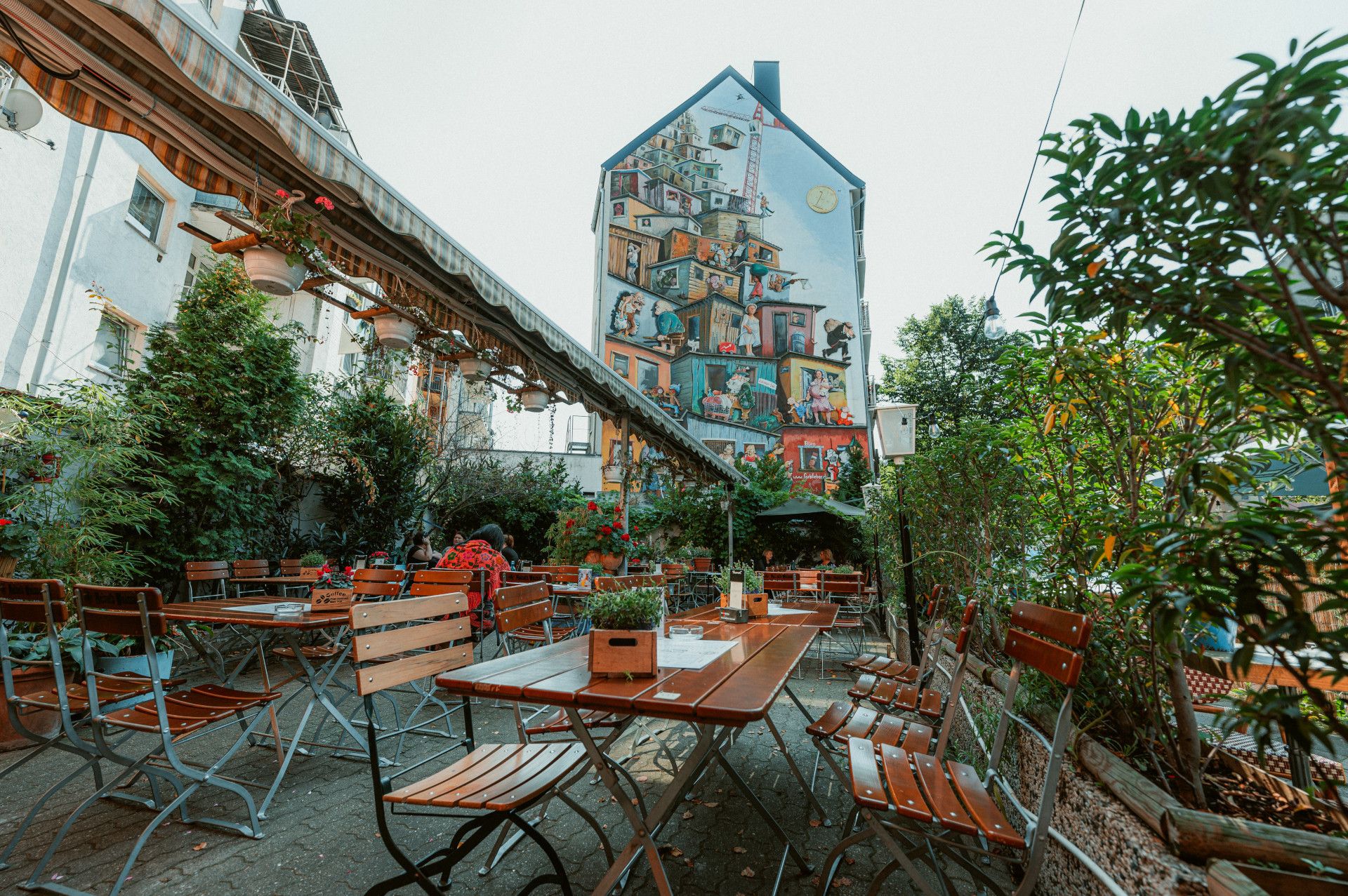 Blick in Tigges Biergarten mit komplett bemalter Hausfassade im Hintergrund