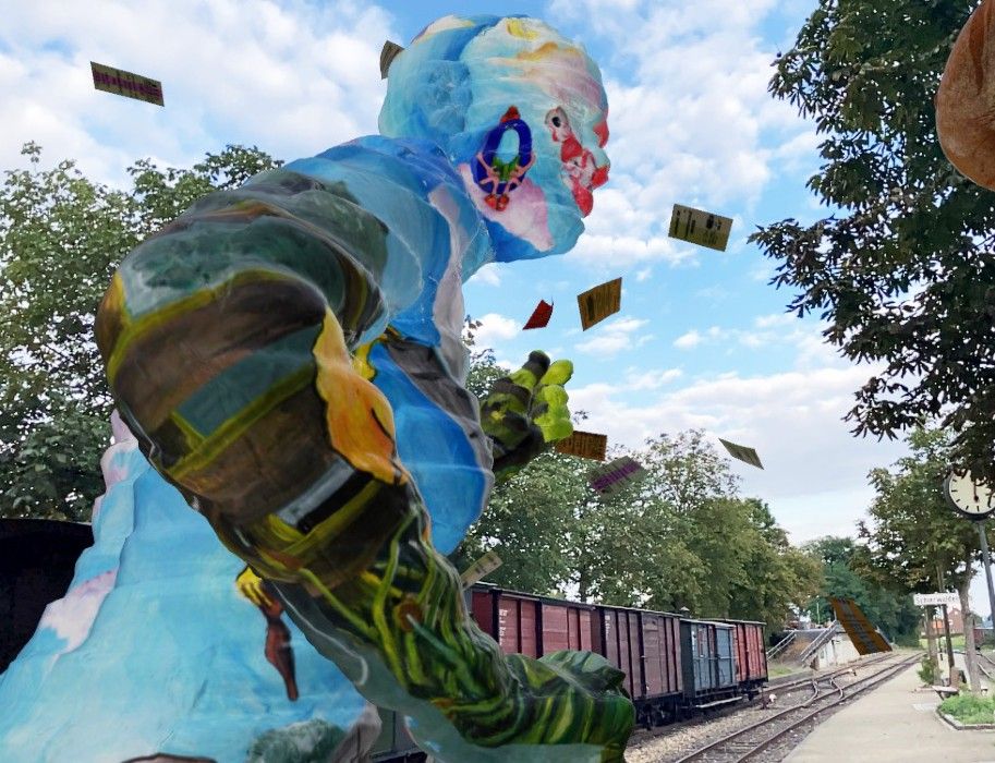 Buntes Kunstwerk in Schierwaldenrath neben Bahngleisen und Bäumen