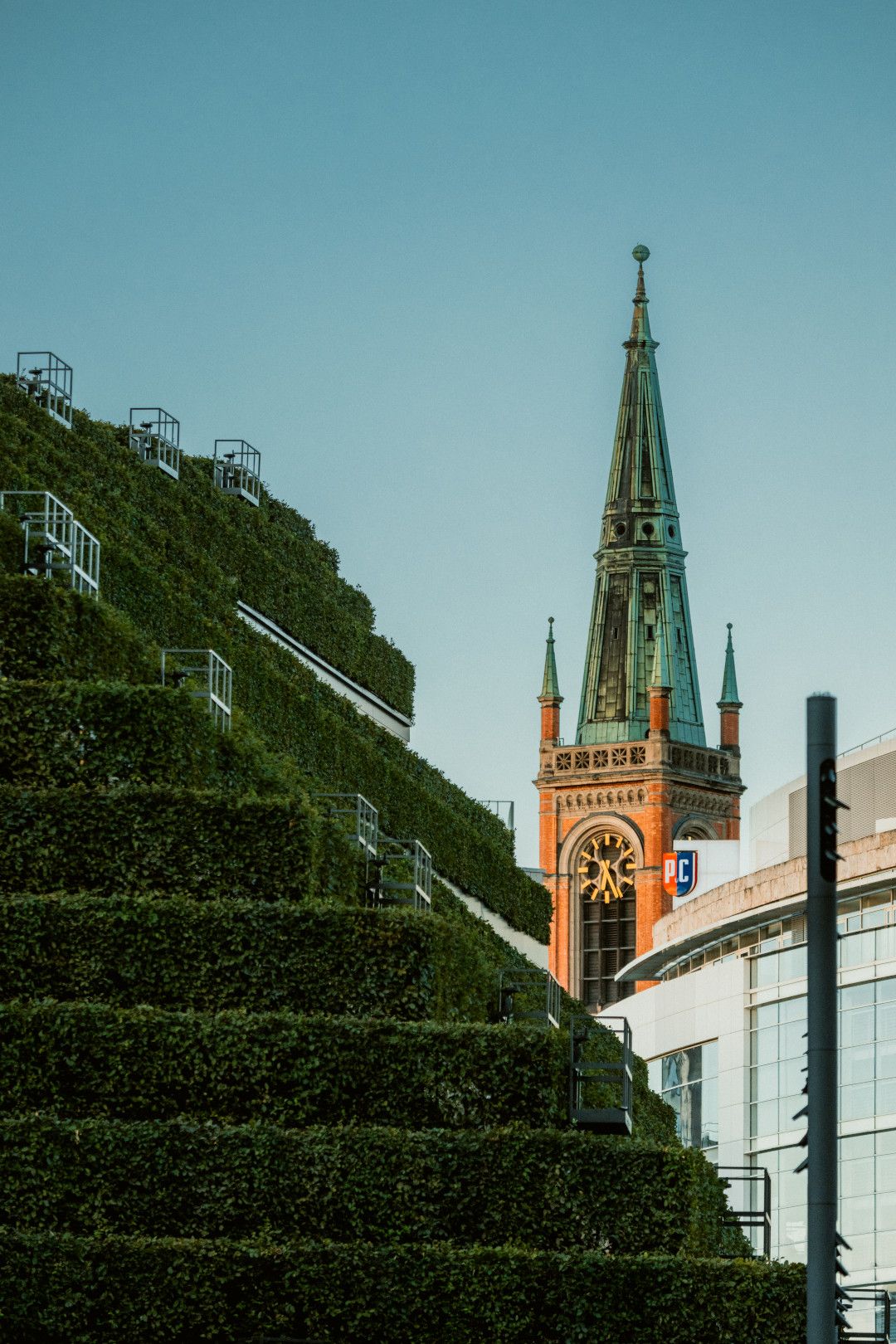 Grüne Fassade des Kö-Bogens in Düsseldorf mit Kirchturm im Hintergrund.