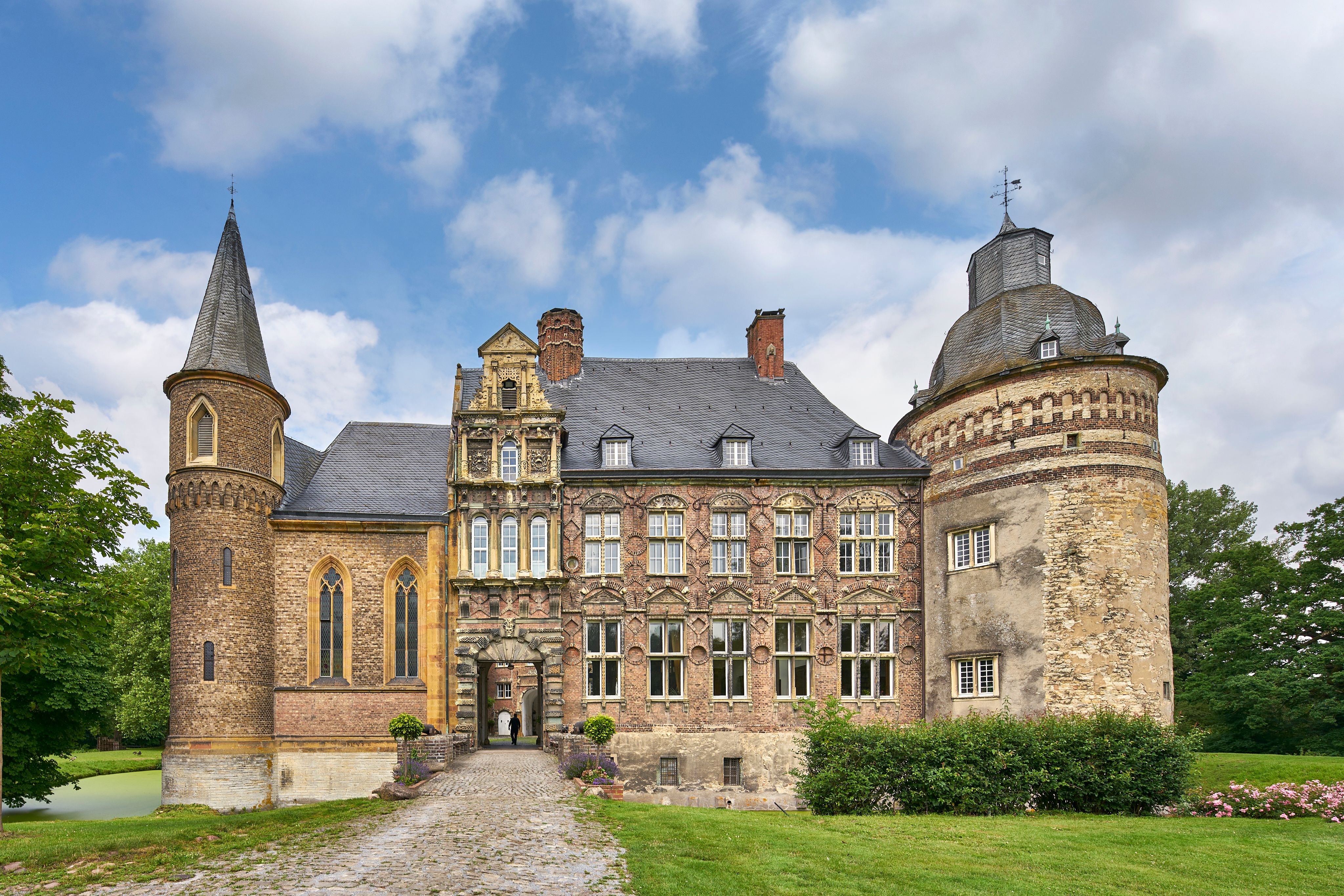 Haus Assen, historisches Gebäude, mit Türmen und verzierten Fassaden vor bewölktem Himmel.