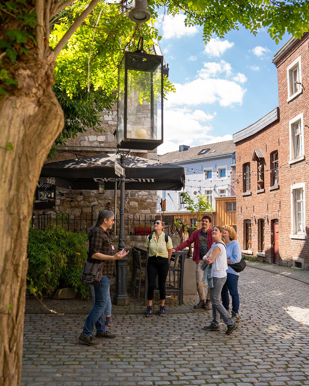 Eine Gruppe von Menschen lauscht einem Stadtführer in der malerischen Altstadt von Stolberg.