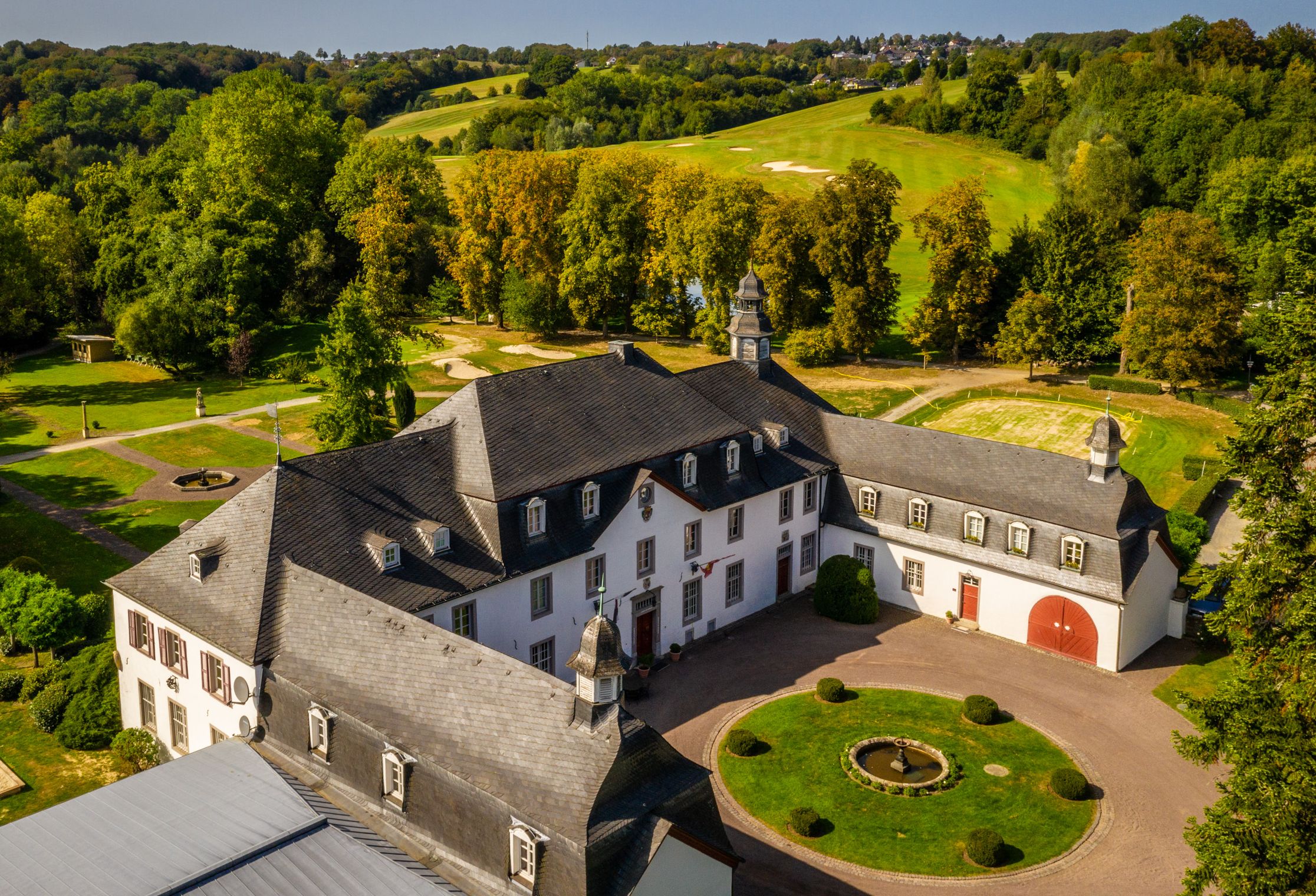 Schloss-Anlage mit Golfplatz und hügeliger Landschaft im Hintergrund