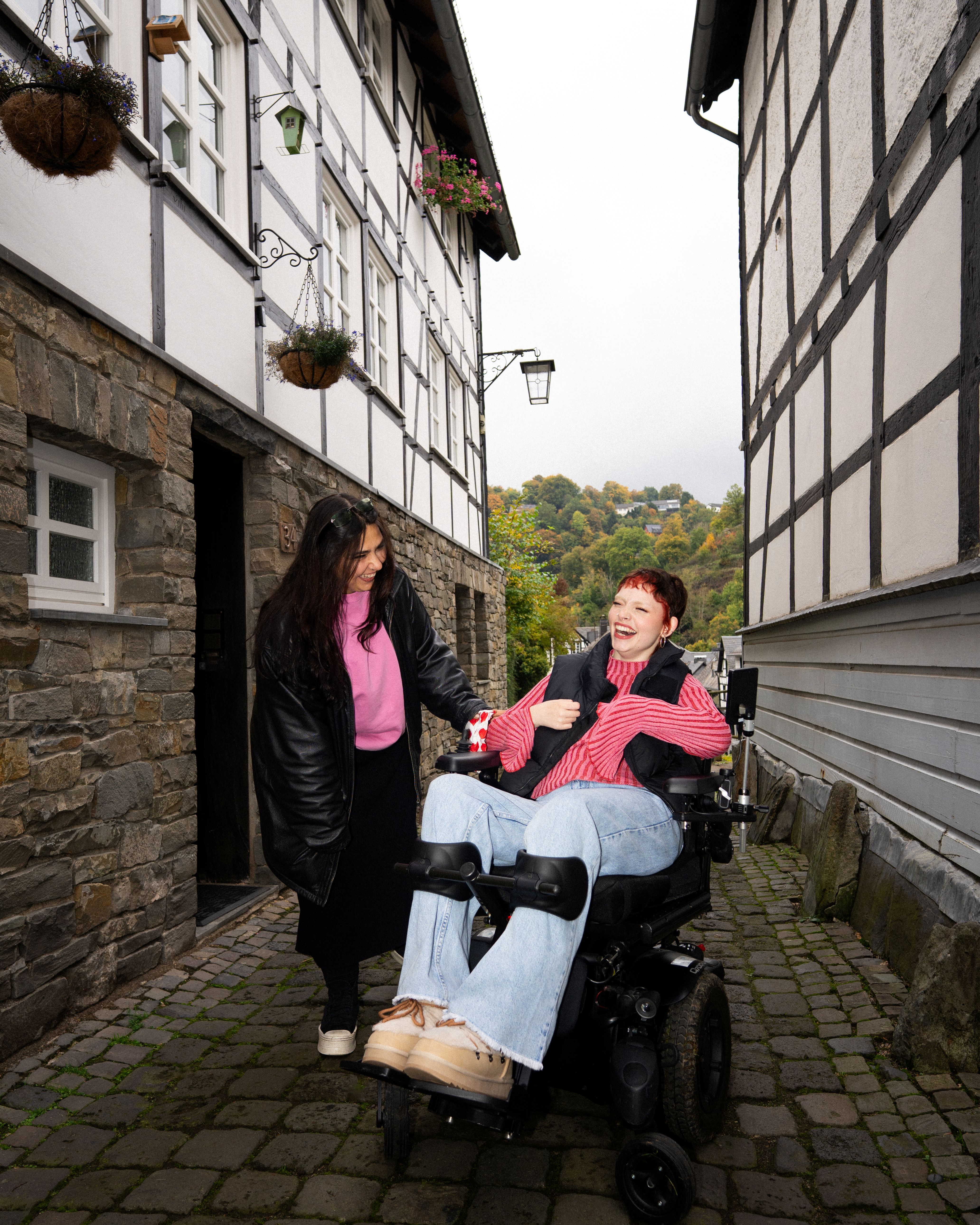 Zwei Freundinnen amüsieren sich in einer Gasse zwischen Fachwerkhäusern in Monschau