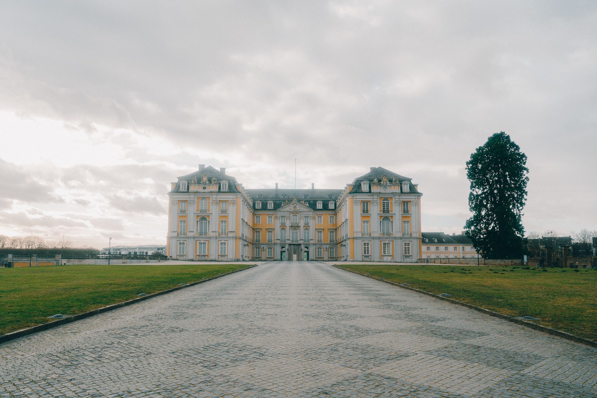 Gepflasterter Weg führt zu gelb-weißem Schloss