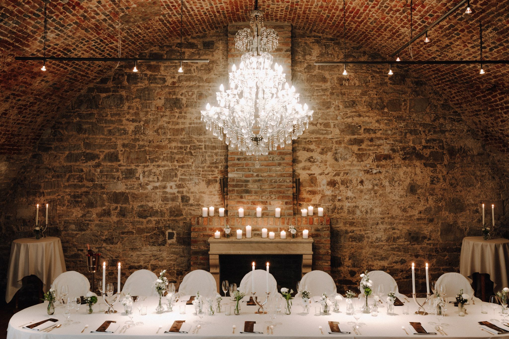 Weiß gedeckter Tisch im mit Kerzen geschmücktem Kellergewölbe