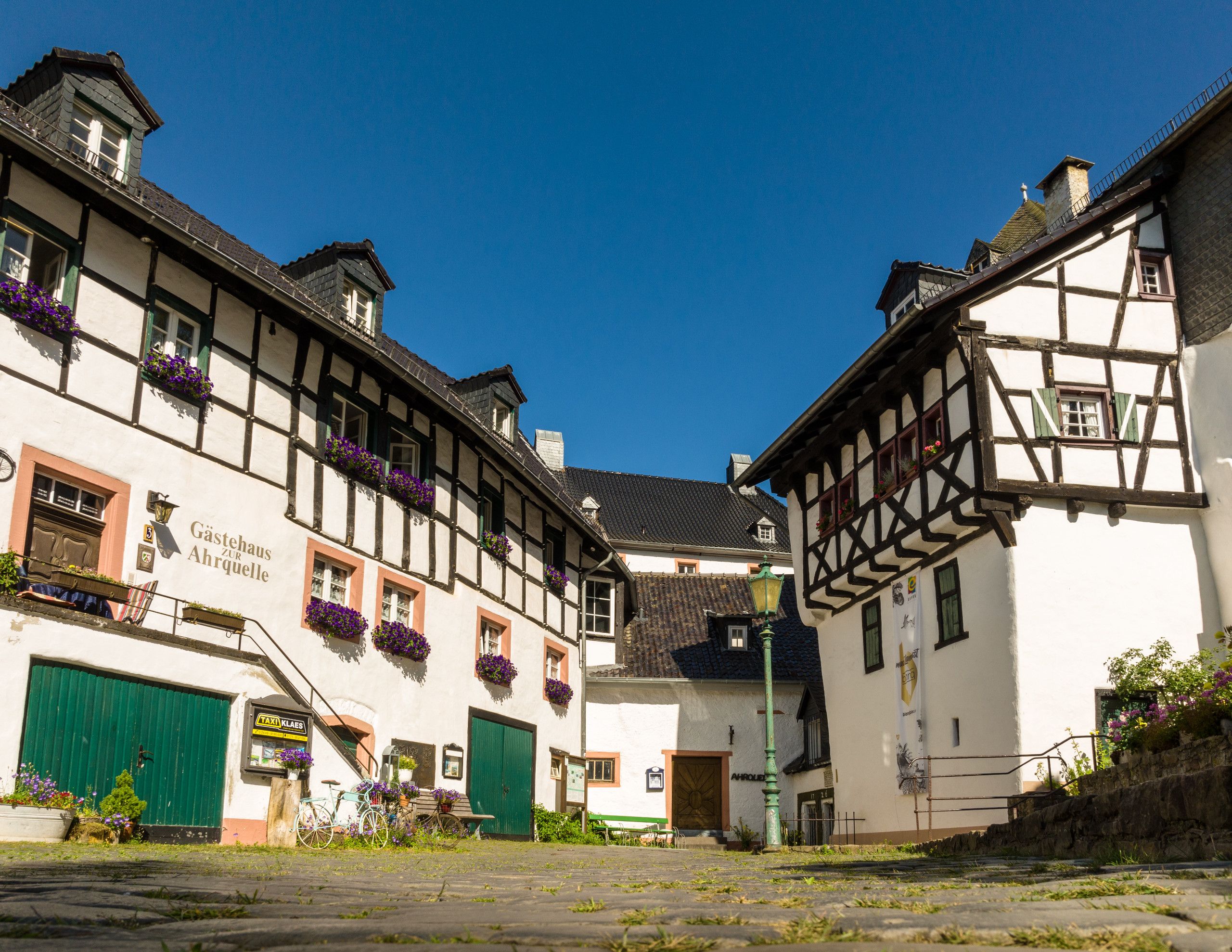 Fachwerkhäuser in Blankenheim mit blauen Fensterläden und Blumenkästen.