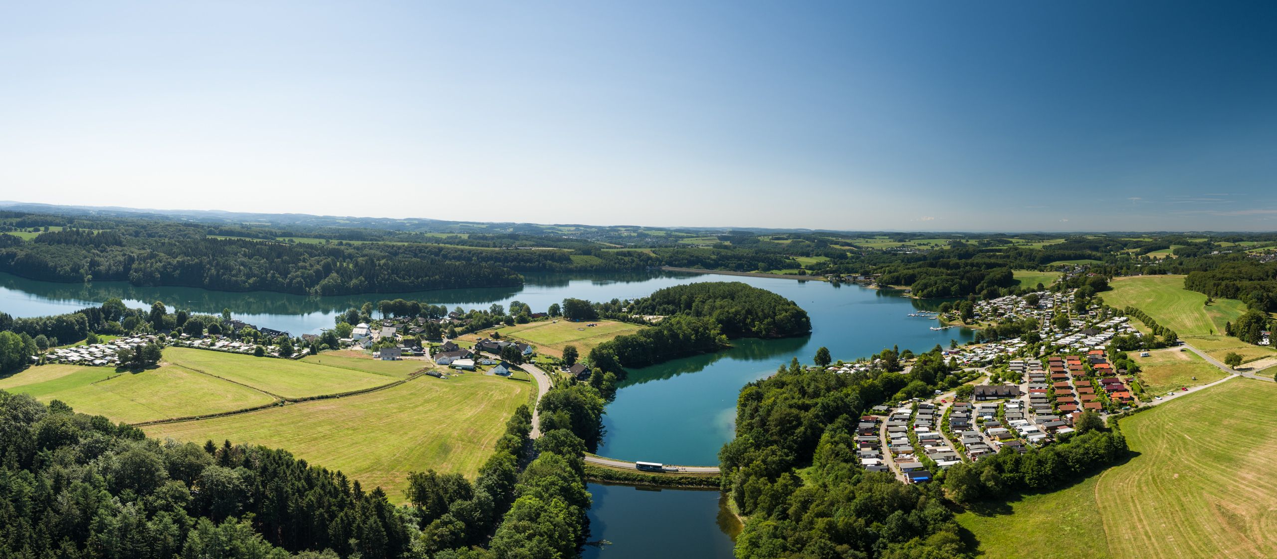 Luftaufnahme der Bevertalsperre mit umliegenden Wäldern und Siedlungen.