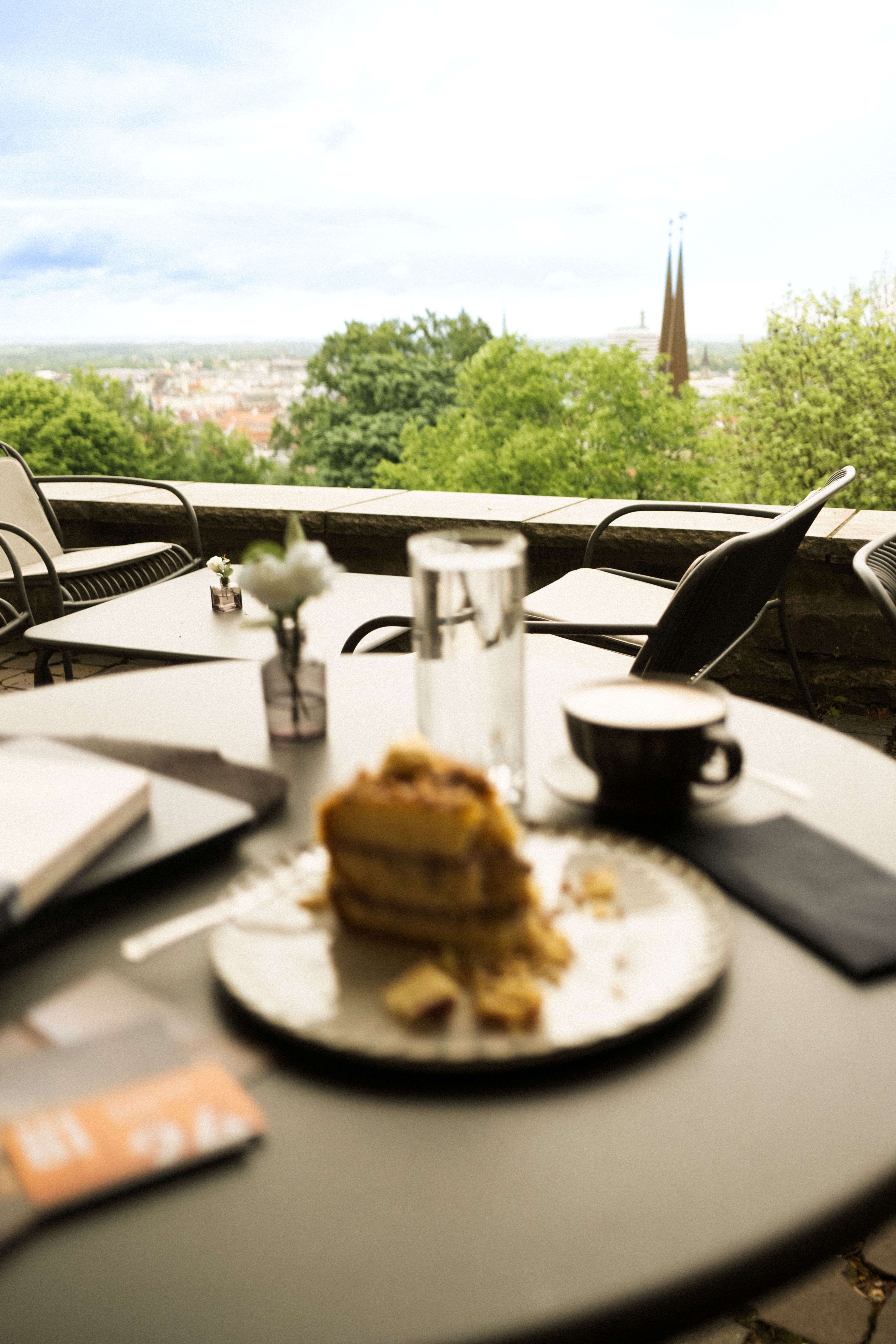 Ein gedeckter Tisch mit Kaffee und Kuchen mit der Stadt Bielefeld im Hintergrund.