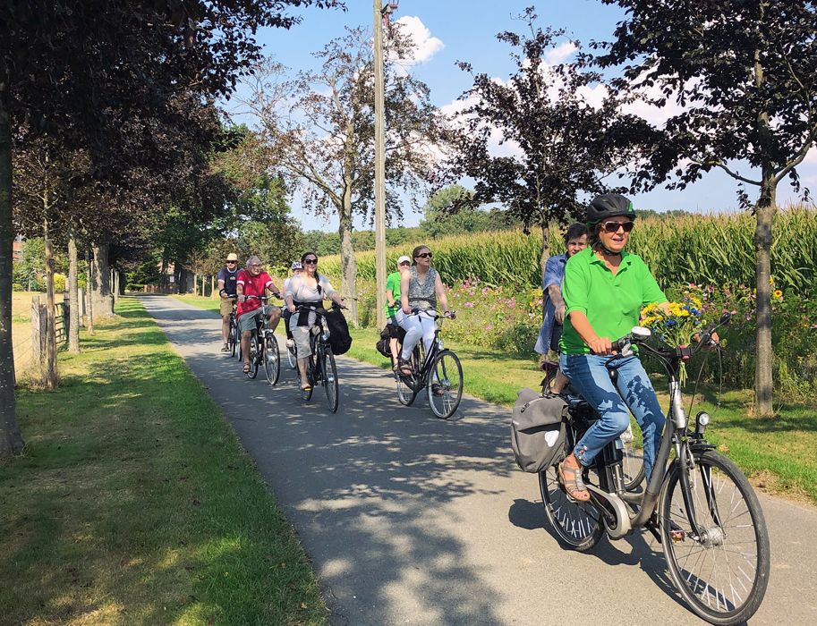 Gruppe von Radfahrern auf einem ländlichen Weg bei sonnigem Wetter.
