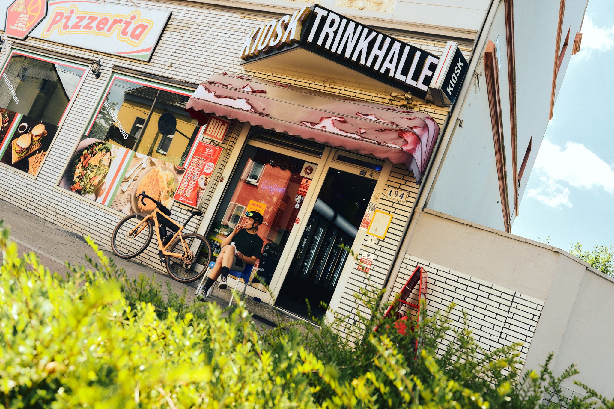 Person sitzt vor einer Trinkhalle mit Fahrrad im Ruhrgebiet.