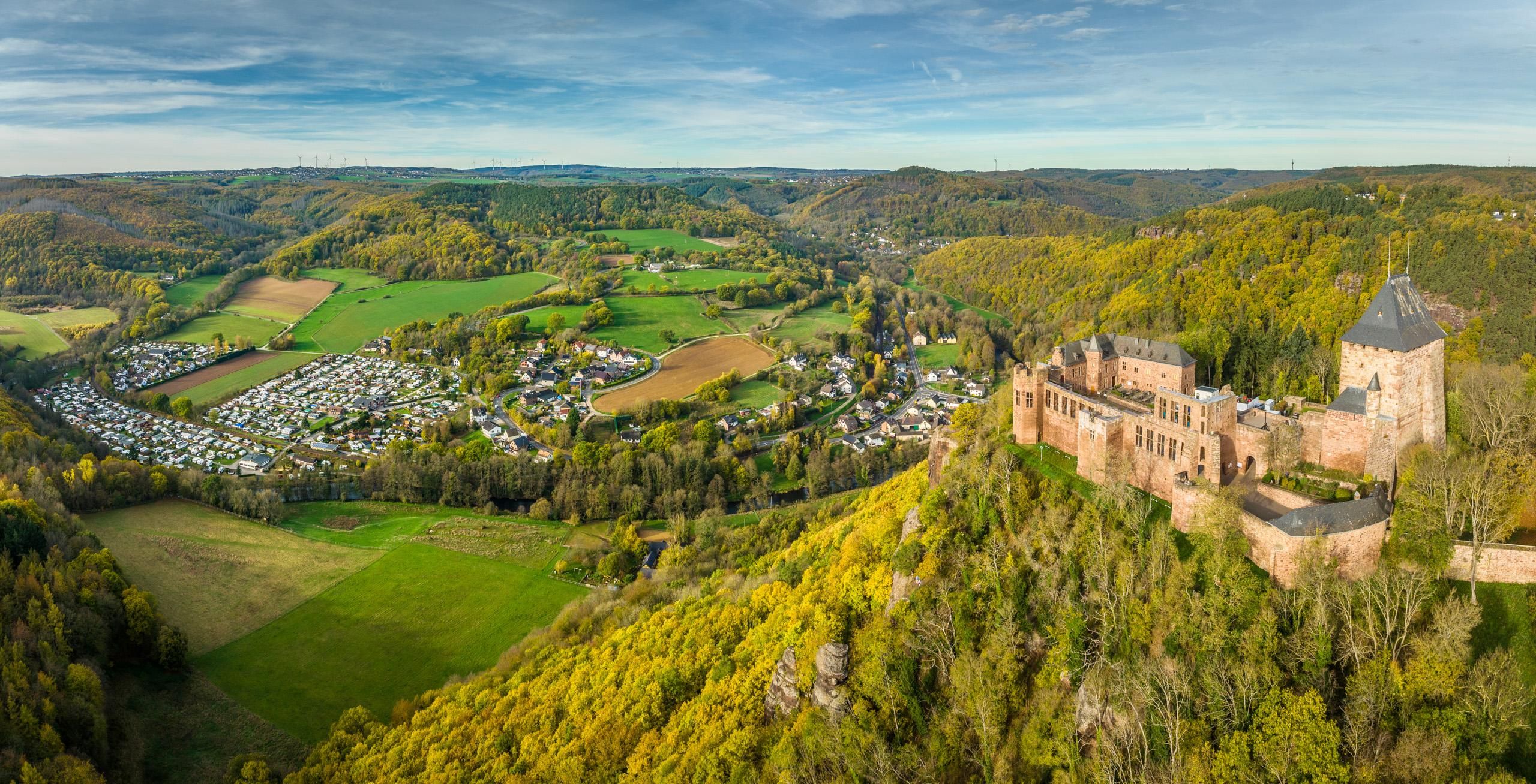 Luftaufnahme der Burg Nideggen inmitten einer grünen Landschaft mit Dorf.