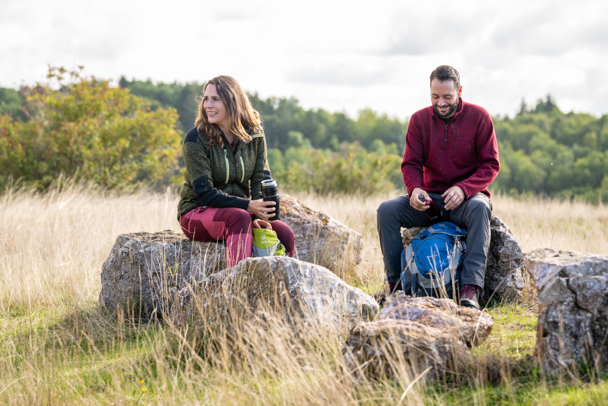 Zwei Personen sitzen auf Felsen in der Natur und machen eine kurze Pause.