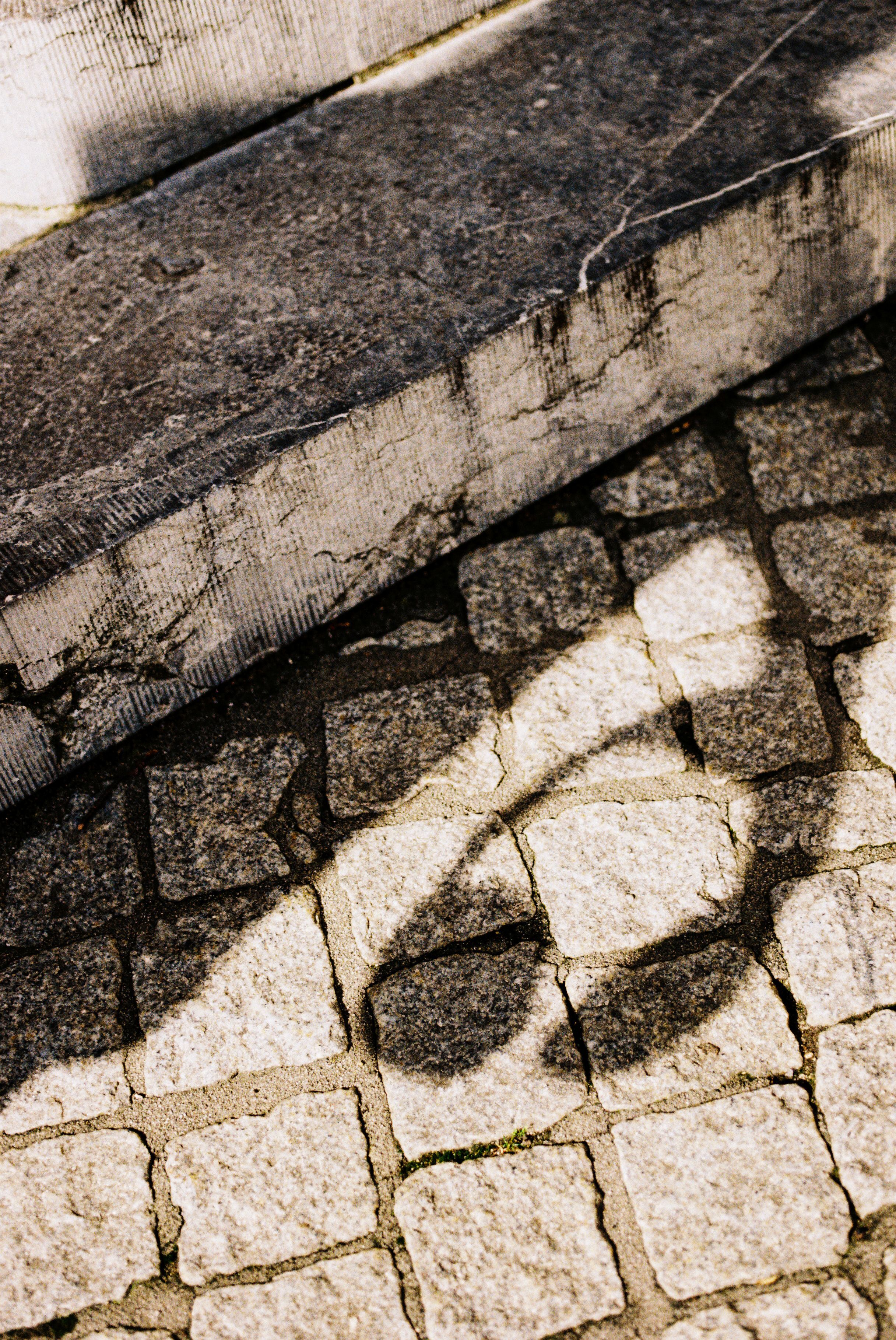 Schatten von Kopfhörern auf Pflastersteinweg in Aachen.