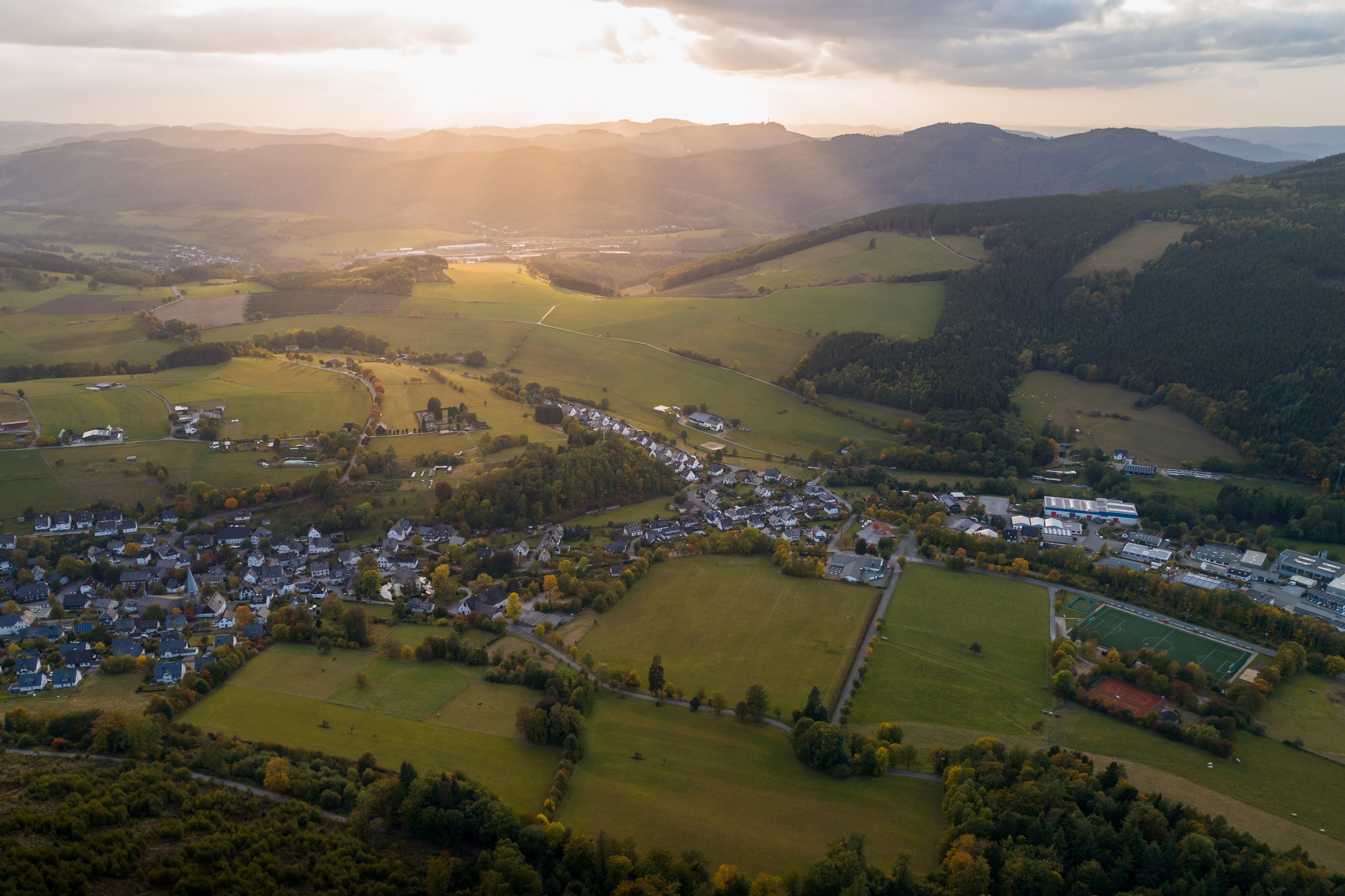 Luftaufnahme von Olsberg mit umliegenden Feldern und Wäldern bei Sonnenuntergang.