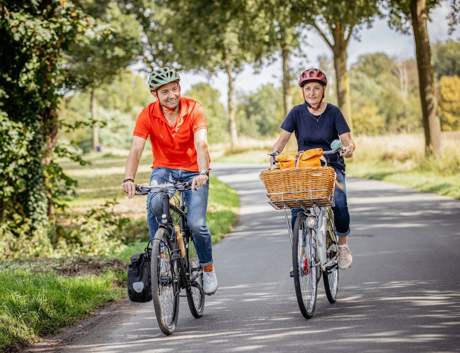 Zwei Personen fahren auf Fahrrädern auf einem ländlichen Weg. Die Friedensroute verbindet die historischen Rathäuser von Münster und Osnabrück mit einem abwechslungsreichen Radfernweg.