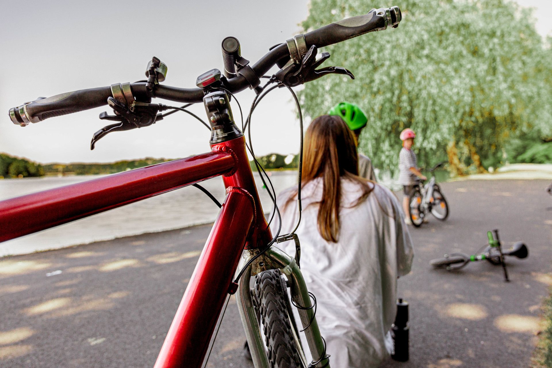 Ein rotes Fahrrad steht im Vordergrund, während im Hintergrund eine Familie gemeinsam Zeit verbringt