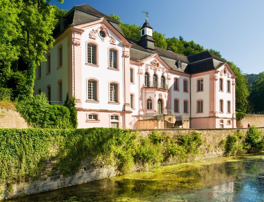 Schloss Weilerbach in Bollendorf, umgeben von Bäumen und einem Wassergraben.