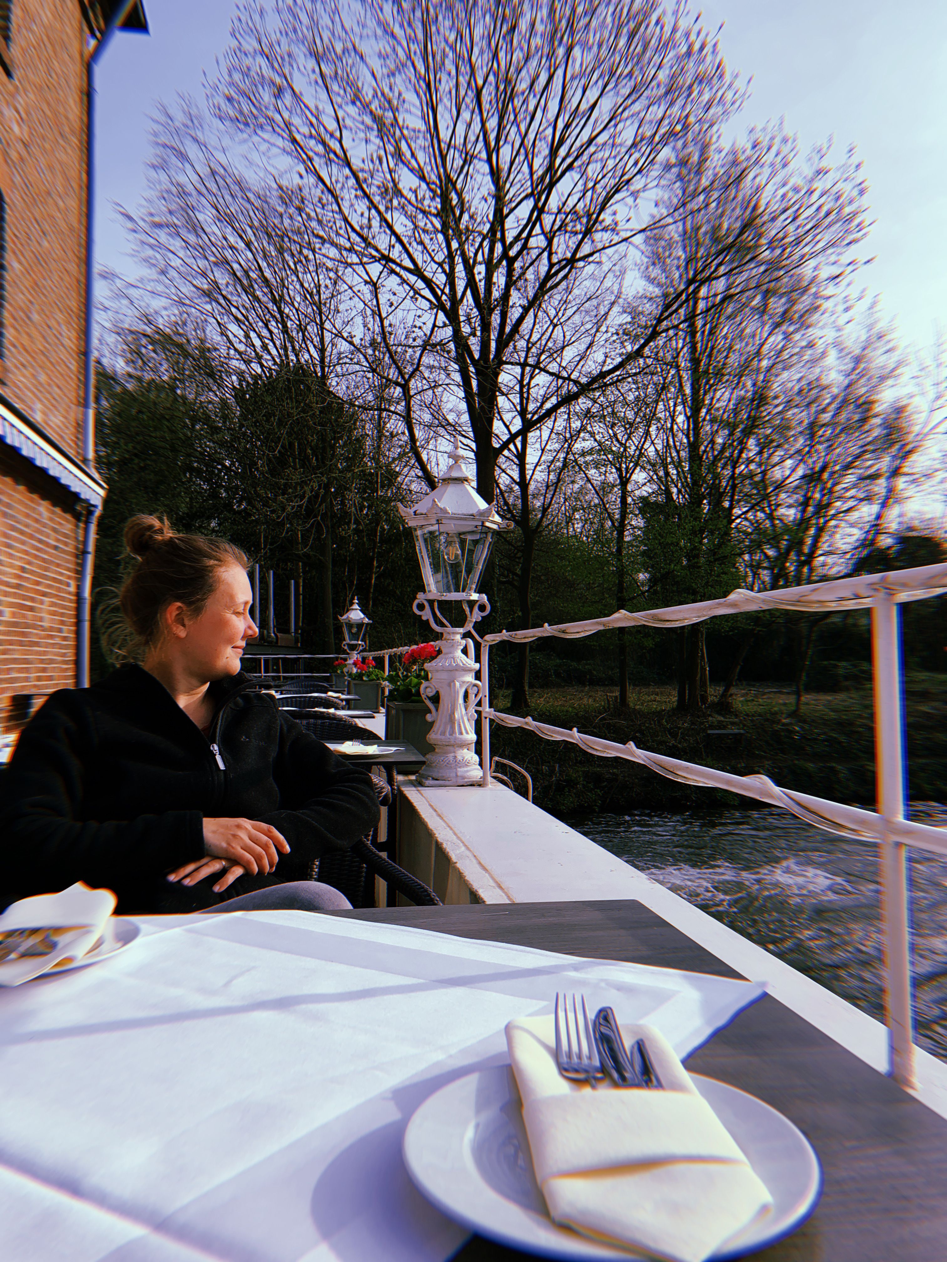 Eine Person sitzt auf der Terrasse der Bedburger Mühle mit dem Kopf zur Erft gerichtet