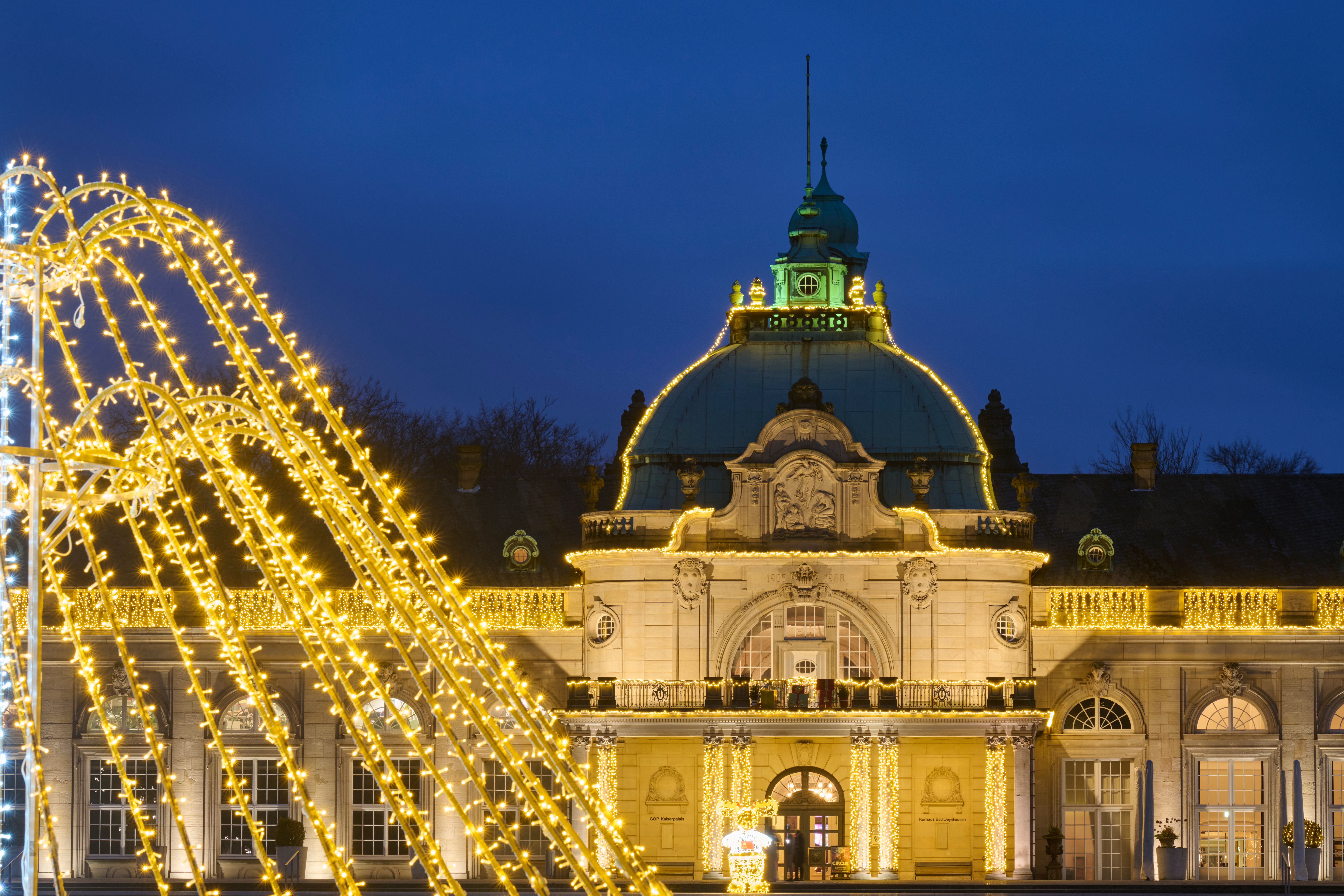 Weihnachtsmarkt Oeynhausen mit festlich beleuchtetem historischem Gebäude und goldenen Lichterketten bei Nacht.