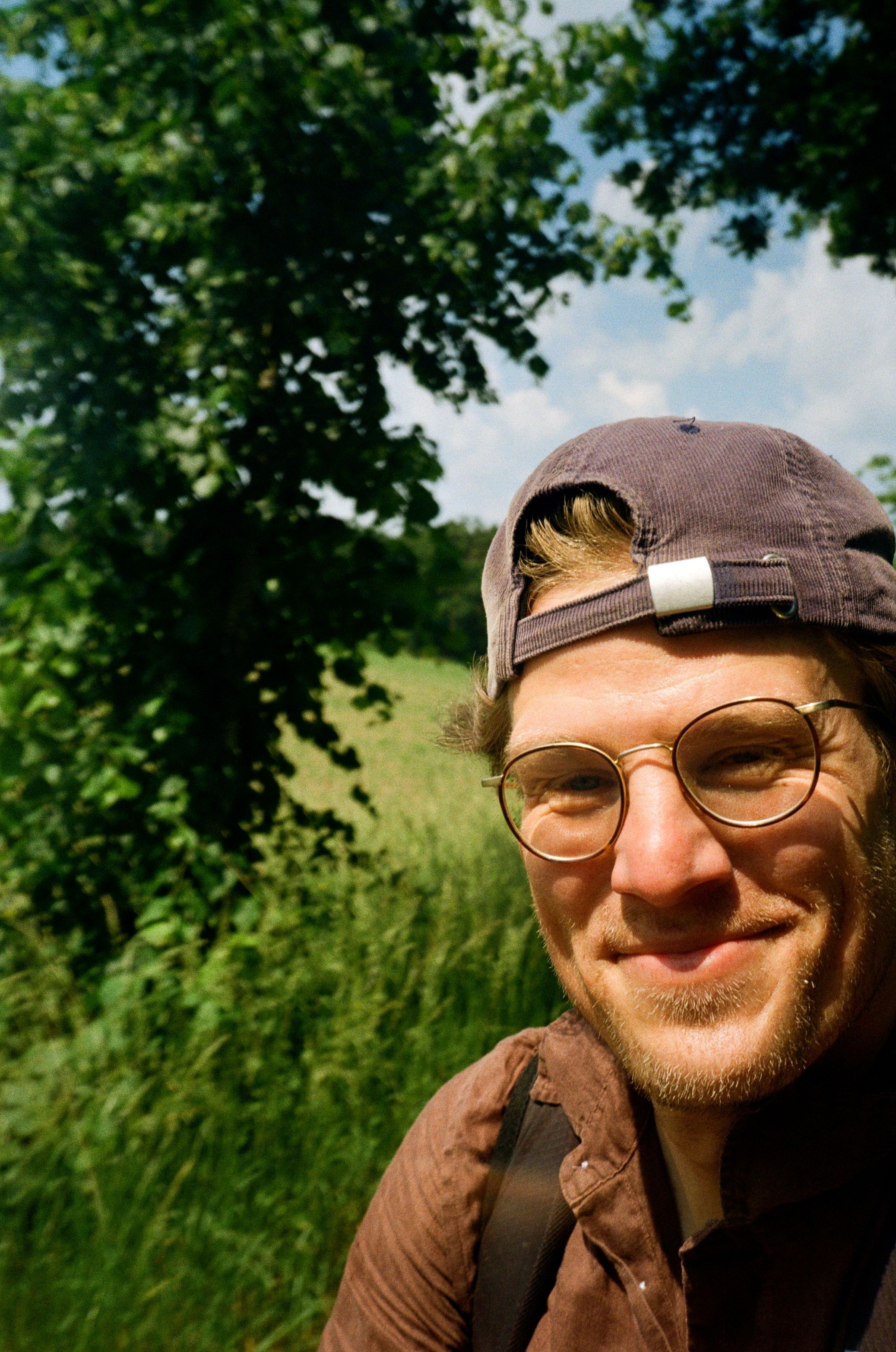 Mann mit Brille und Kappe vor einer grünen Wiese am Niederrhein.
