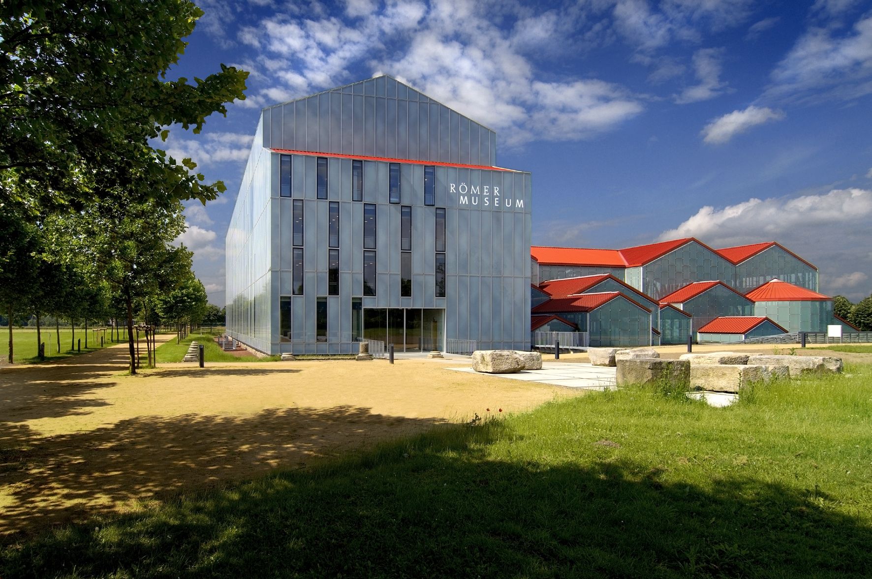 Außenansicht des LVR-Römermuseums mit roten Ziegeldächern vor blauem Himmel