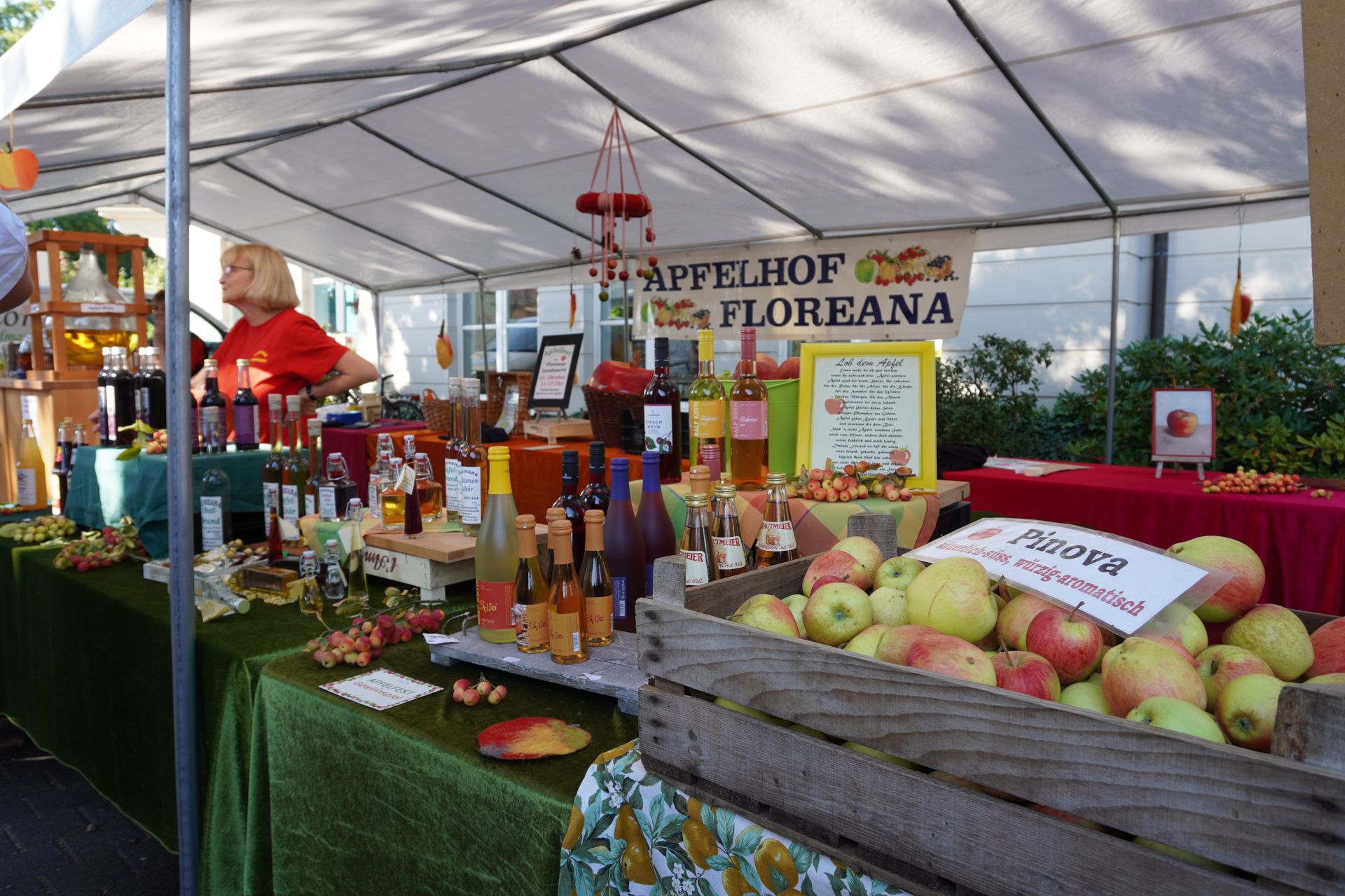 Ein Marktstand mit Apfelprodukten vom Apfelhof Floreana, darunter Säfte und Liköre, unter einem weißen Zelt