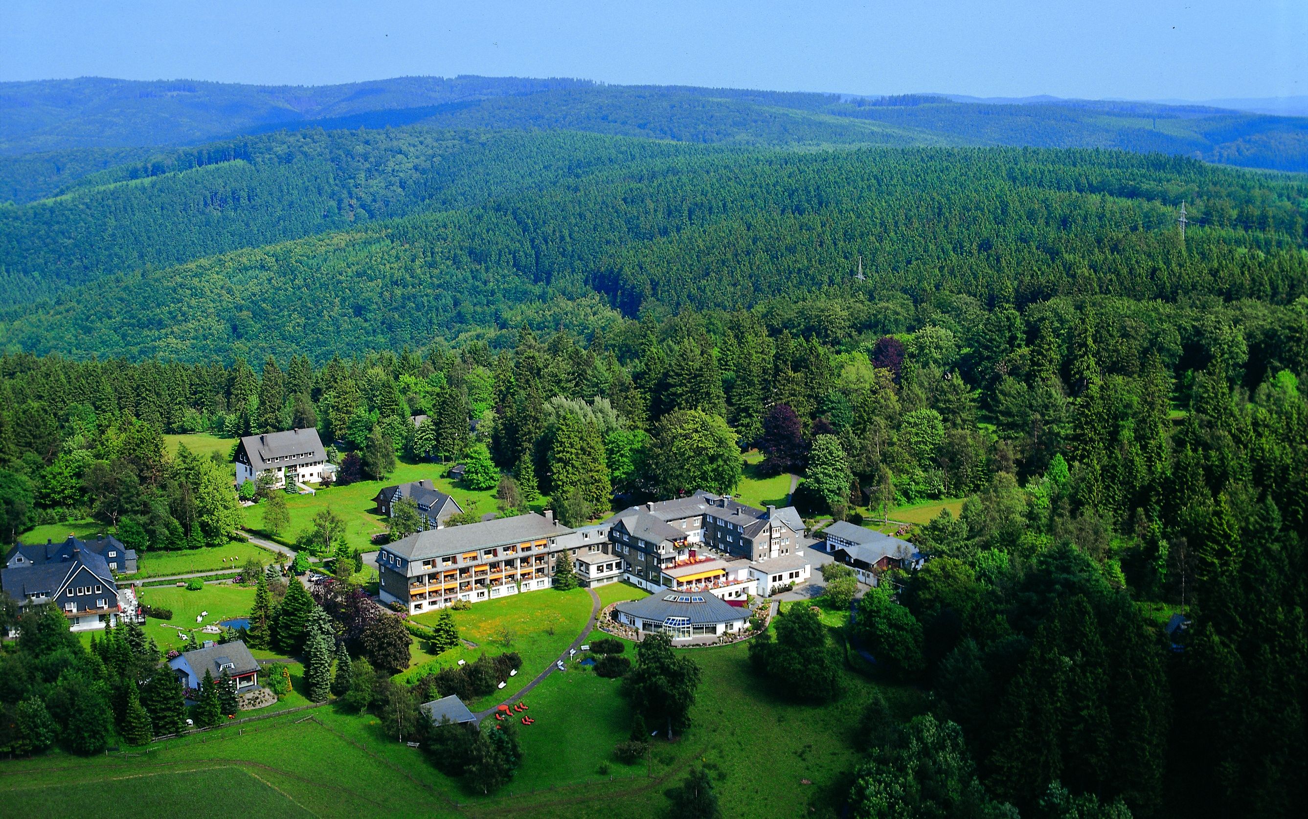 Die Anlage des Hotels Jagdhaus Wiese  liegt eingebettet in eine weite, bewaldete Landschaft.