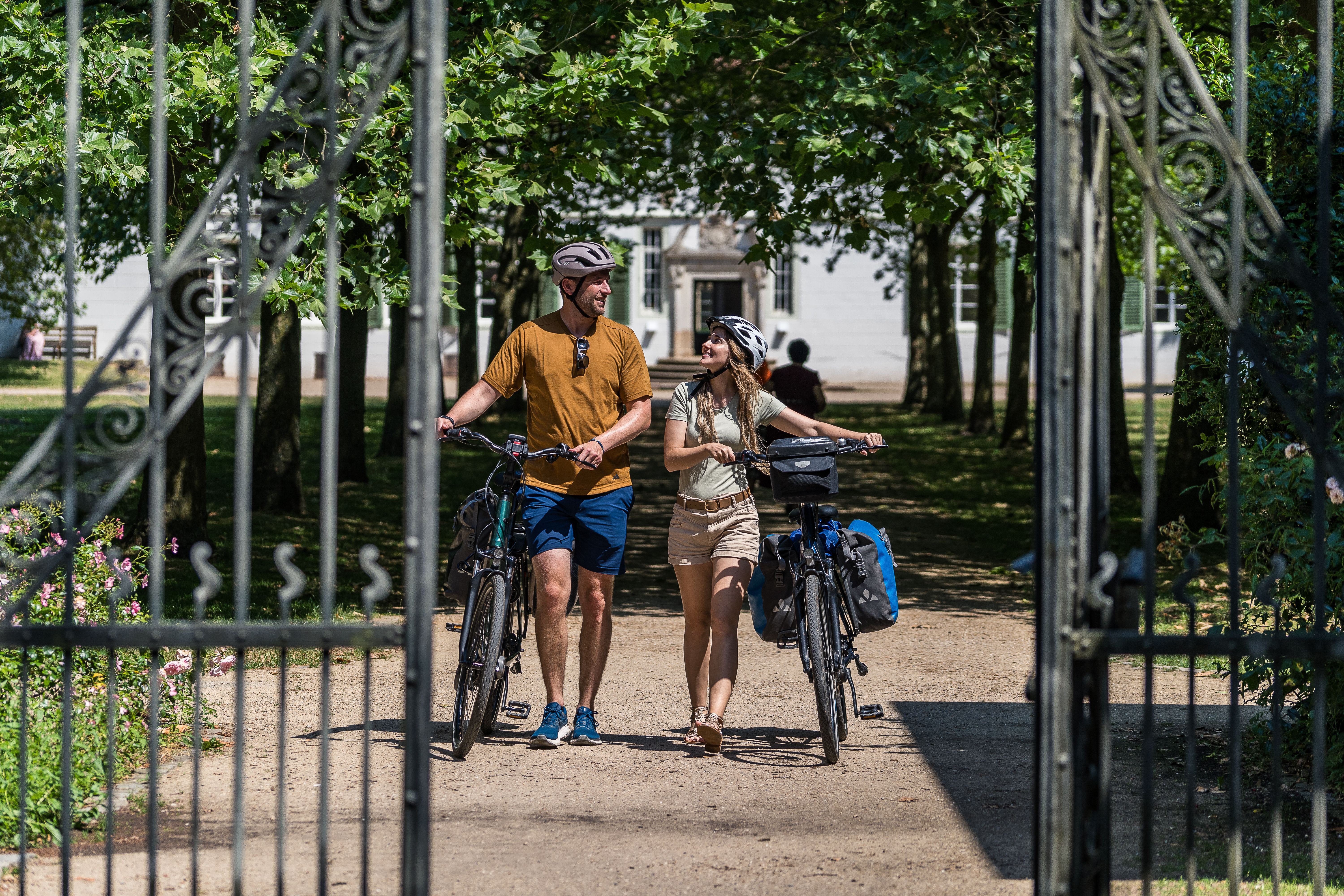Radreisende erkunden den idyllischen Park von Kloster Bentlage bei Rheine und genießen die grüne Oase.