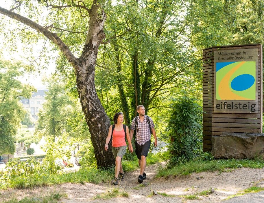 Zwei Wanderer am Eingang des Eifelsteigs in Kornelimünster.