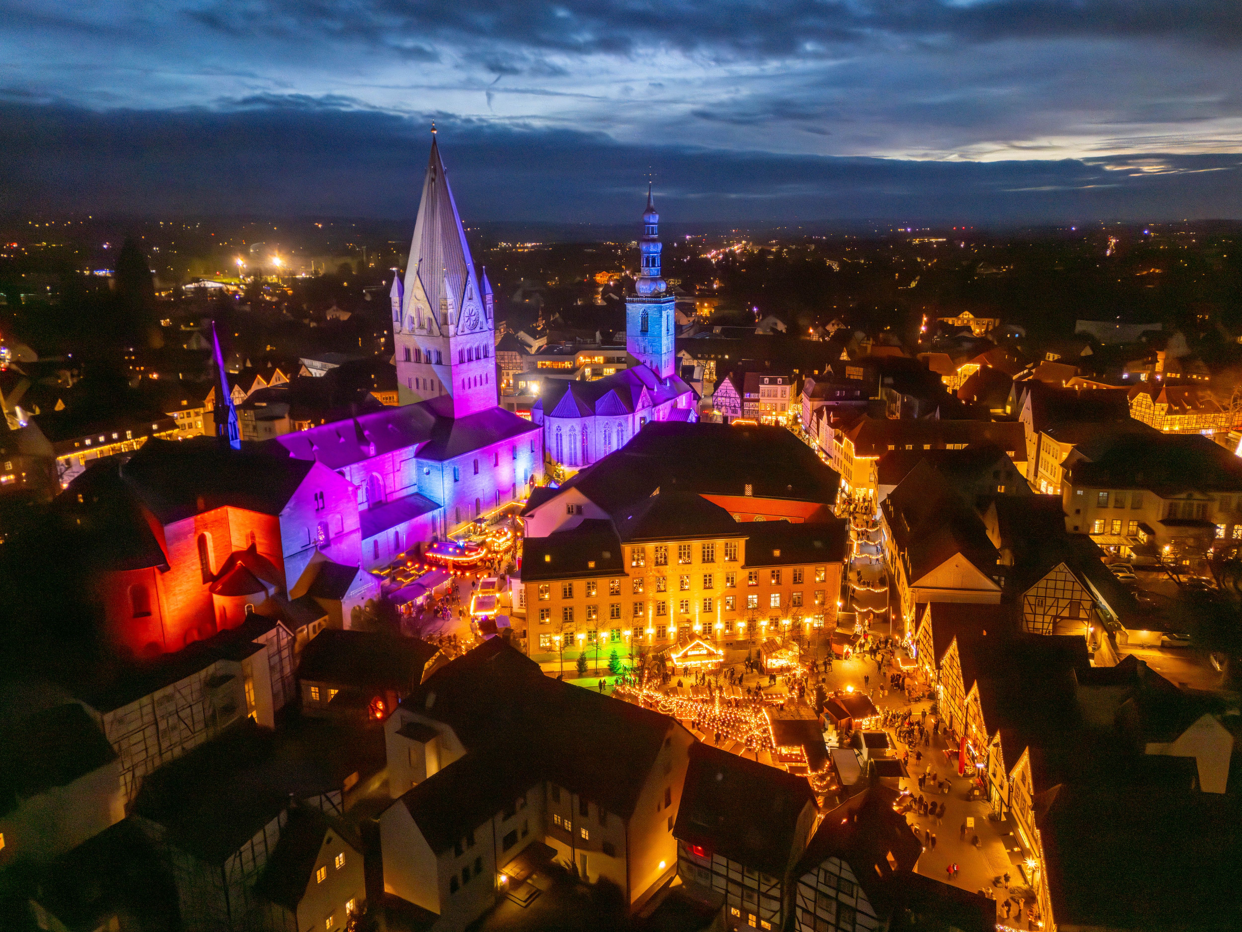 Luftaufnahme des Soester Weihnachtsmarkts bei Nacht mit beleuchteten Gebäuden und Ständen.
