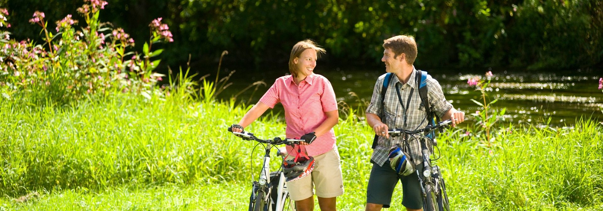 Zwei Personen mit Fahrrädern in einer grünen Landschaft.
