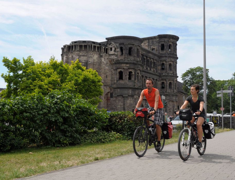 Zwei Radfahrer vor der Porta Nigra in Trier.