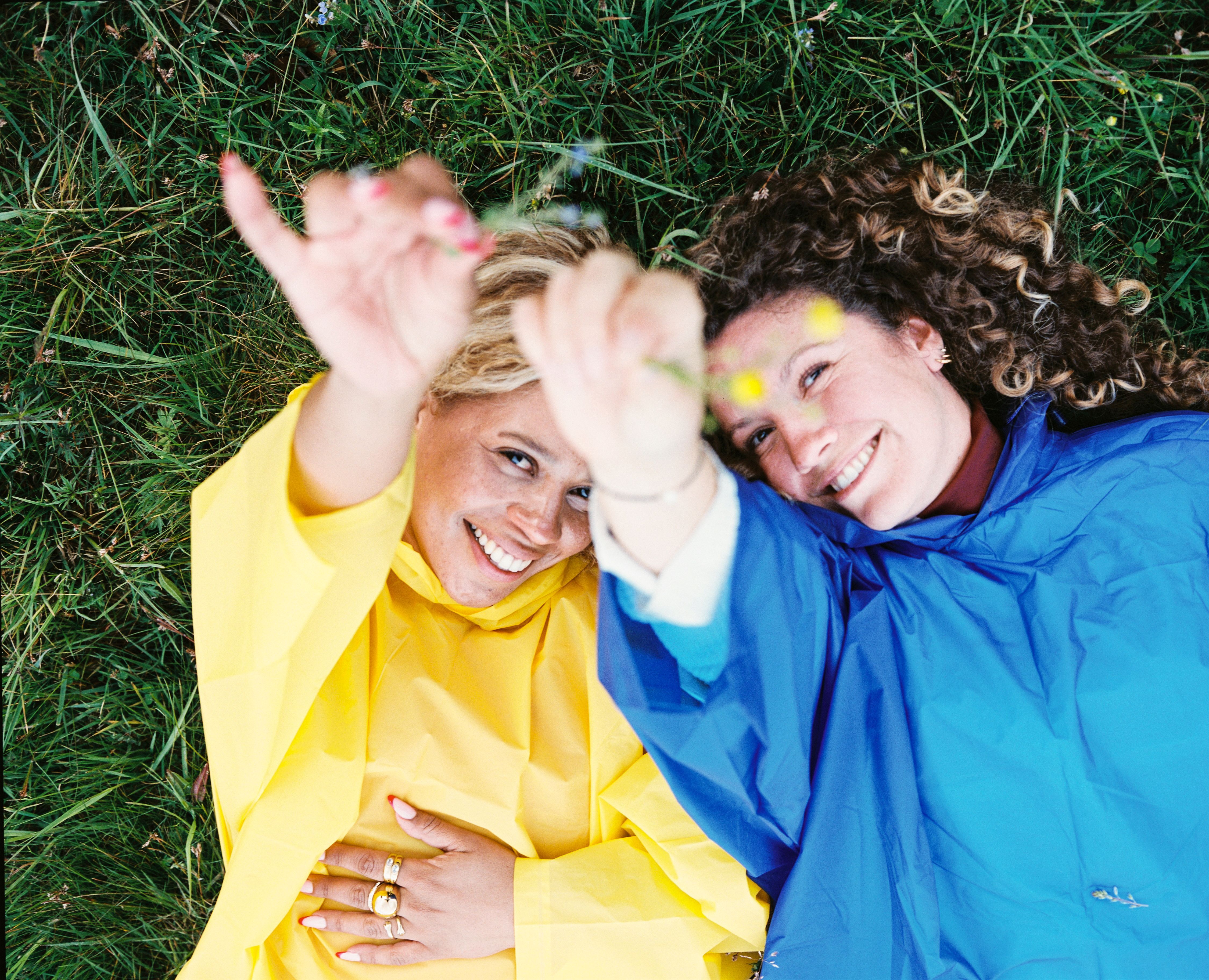 Zwei Frauen in Regenmänteln auf einer Wiese in der Eifel.