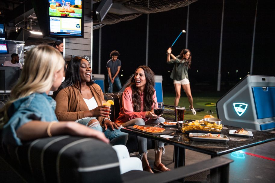 Menschen genießen Essen und Getränke in einer Golf-Lounge.